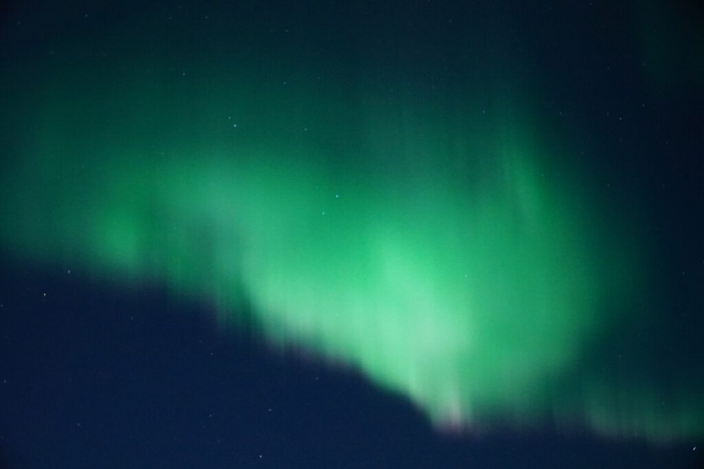 Hjertholmen Lødingen Northern Lights forming a wide green aurora curtain across a clear Arctic night sky