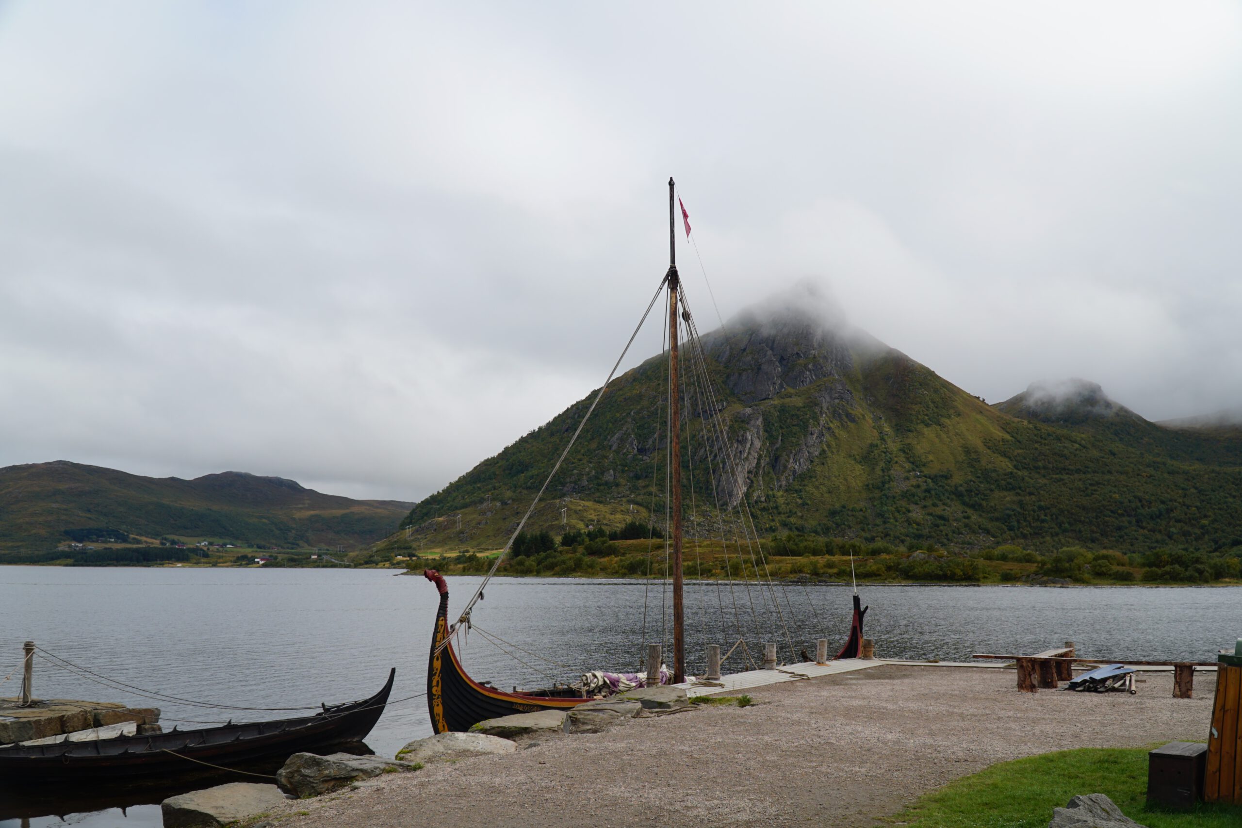 Lofotr Viking Museum outdoor Viking ship Vargfotr moored by the water with mountains in the background at the Borg site on Vestvågøy, Lofoten Islands