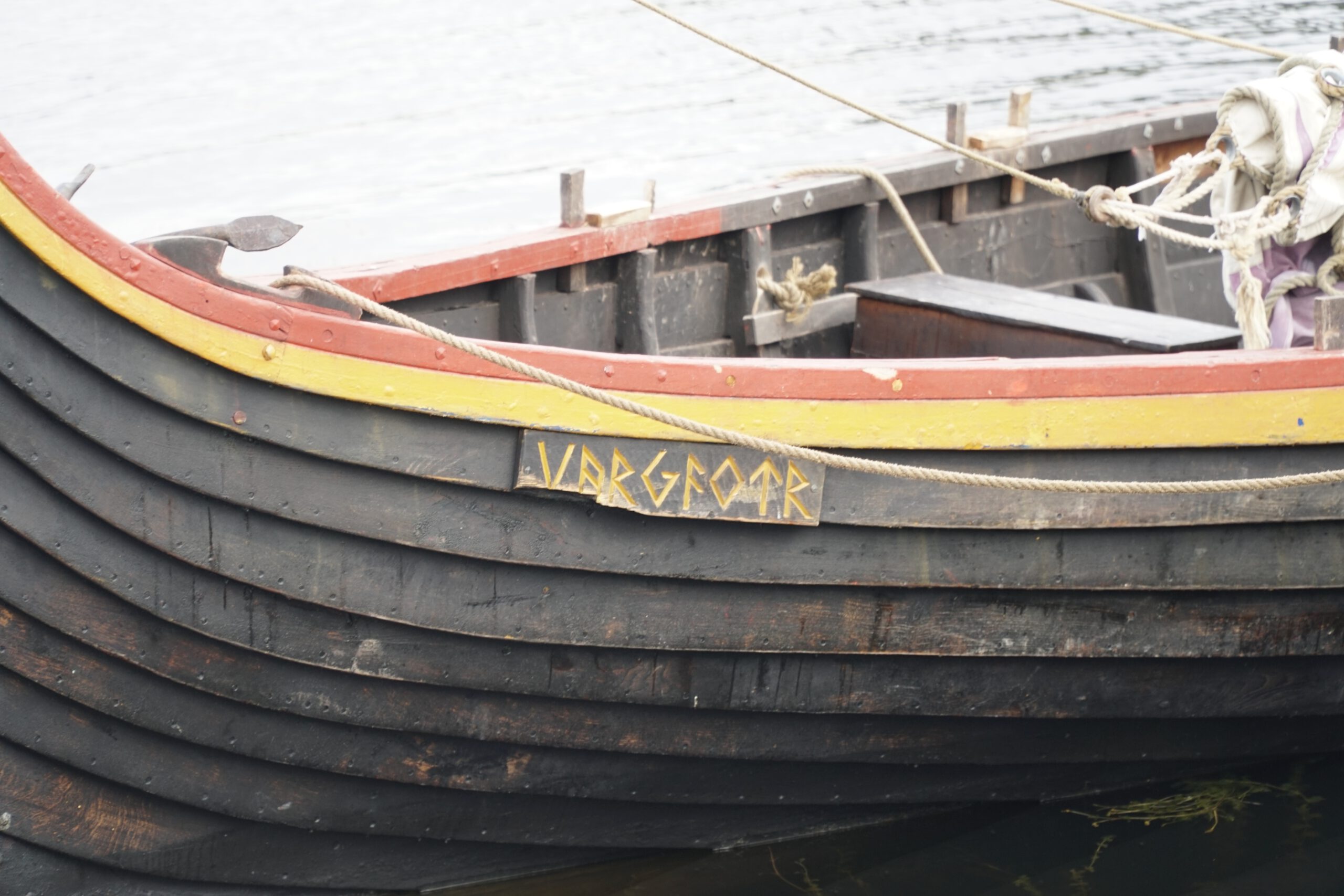 Lofotr Viking Museum traditional Viking ship detail showing the wooden hull of the Vargfotr boat docked on the museum grounds in Borg, Lofoten Islands