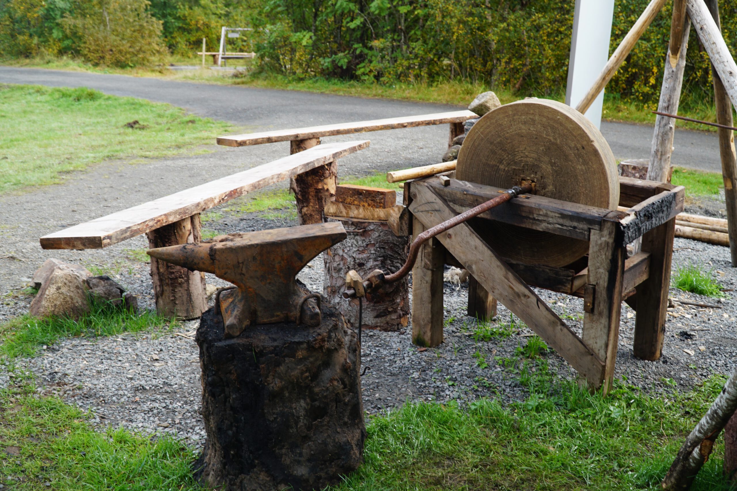 Lofotr Viking Museum outdoor blacksmith area with anvil, grinding stone and wooden workbenches used to demonstrate traditional Viking craftsmanship at the Borg site