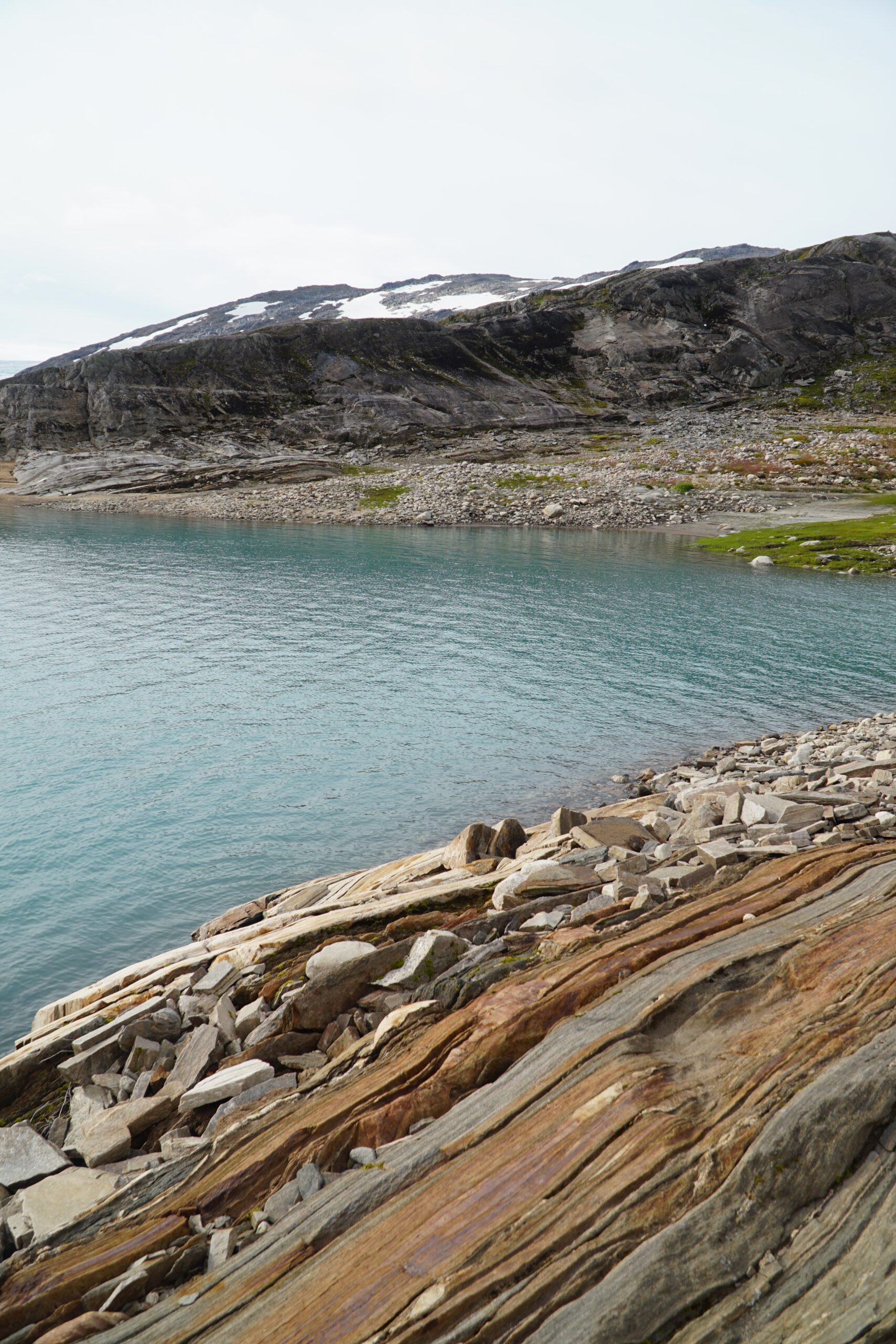 Turquoise glacial water of Storglomvatnet surrounded by layered rock formations and rugged Norwegian mountain scenery