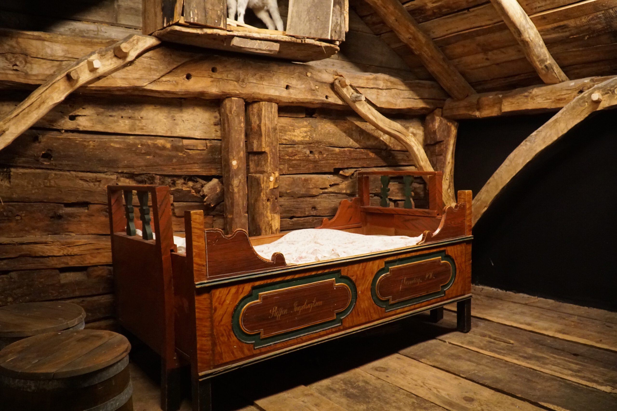 Historic Norwegian farmhouse bedroom reconstruction at Norsk Fjordsenter Geiranger featuring a carved wooden bed inside a timber cabin, UNESCO World Heritage Geirangerfjord cultural exhibit
