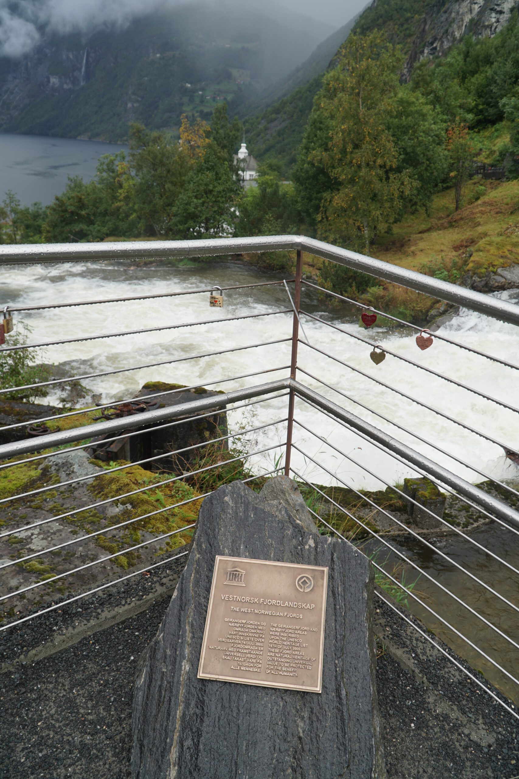 UNESCO World Heritage plaque for Vestnorsk fjordlandskap at Norsk Fjordsenter Geiranger overlooking the powerful river and Geirangerfjord landscape in Norway