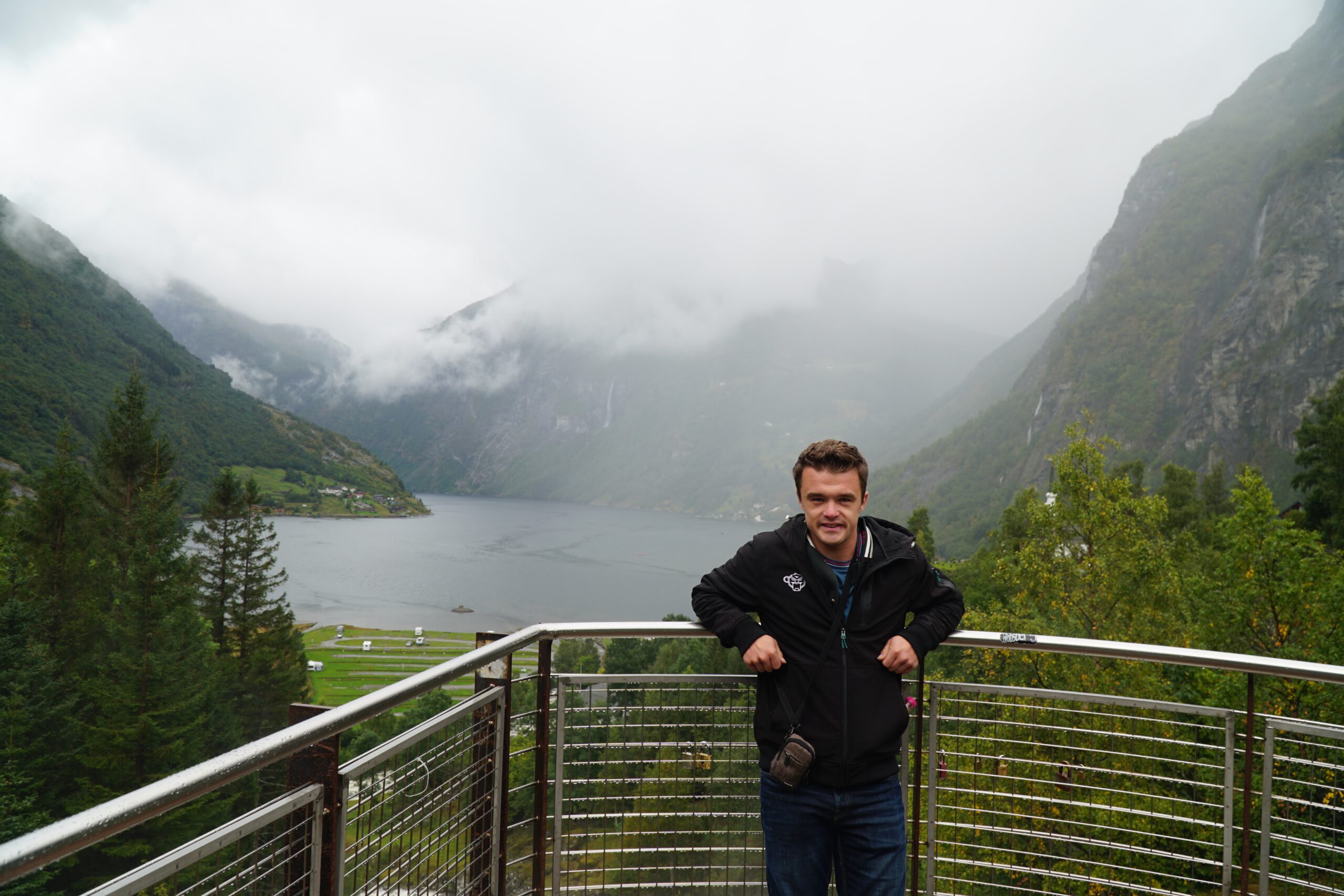 Peter Smit at viewing platform near Norsk Fjordsenter Geiranger with panoramic view over the UNESCO World Heritage Geirangerfjord and dramatic Norwegian fjord scenery