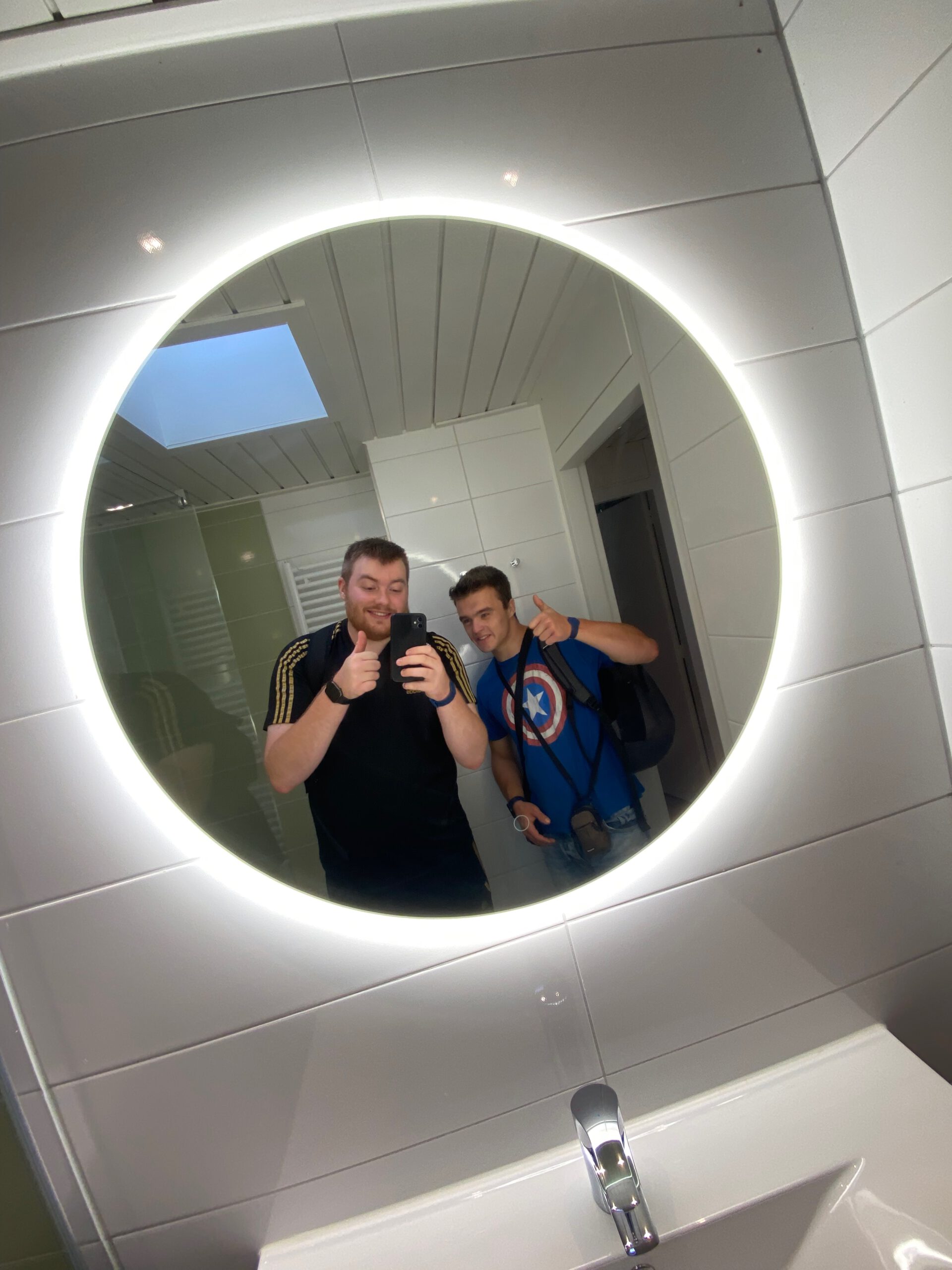 Timo van den Berg Timeuw and Peter Smit in the bathroom of Center Parcs Het Heijderbos 4 pers. Premium HB1922 cottage 965, mirror selfie showing modern shower and illuminated round mirror.