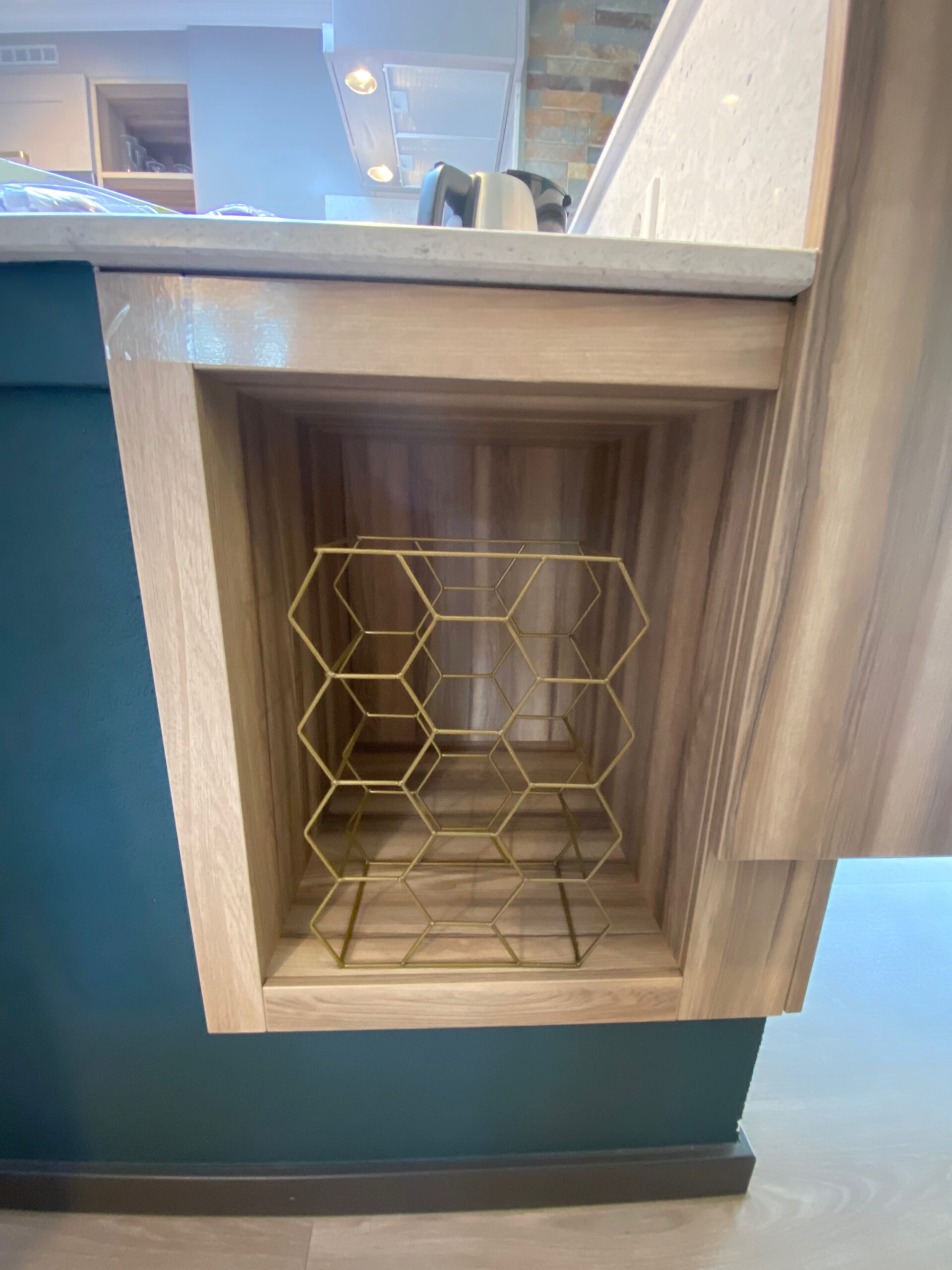 Built in golden hexagon wine rack detail inside Center Parcs Het Heijderbos VIP cottage 978, integrated in natural wood kitchen cabinet under the countertop.