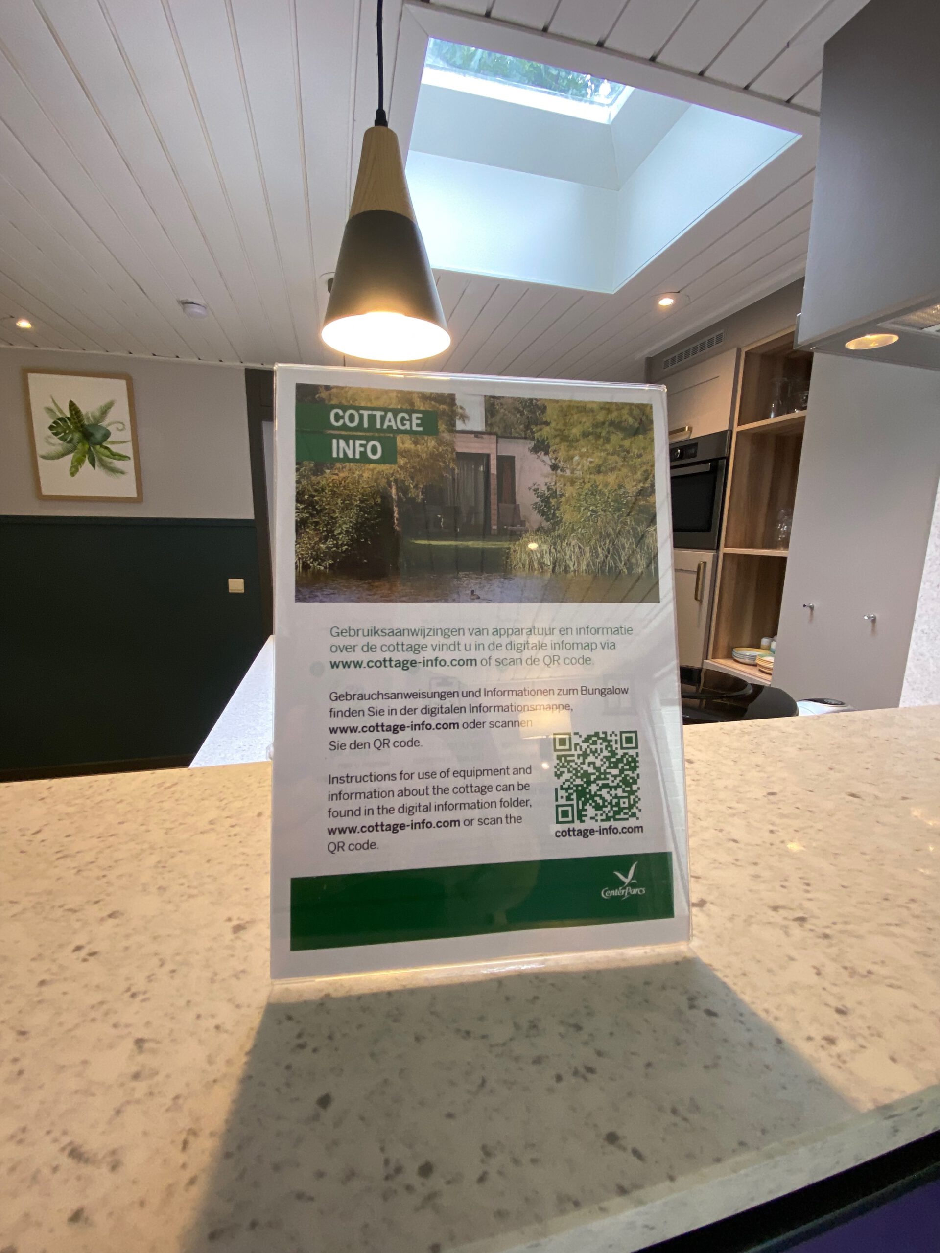 Cottage information display inside Center Parcs Het Heijderbos VIP cottage 978, modern kitchen island with natural stone finish, skylight above and renovated VIP interior details.