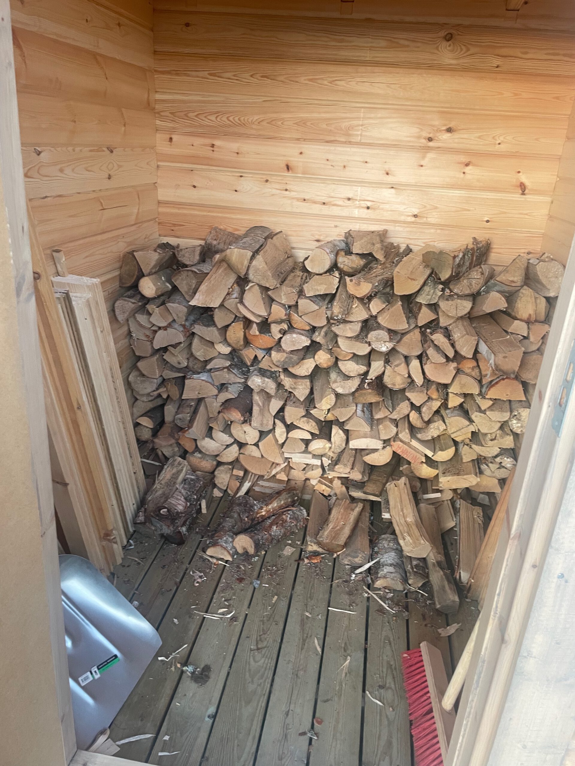T4 Wintertrail Kota Sweden firewood storage filled with stacked logs, available wood supply for heating and cooking at remote forest shelter