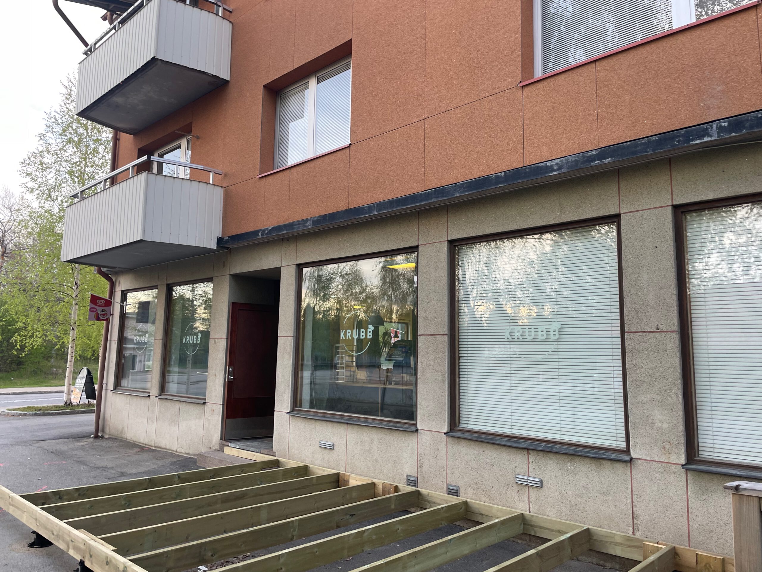 Exterior of Töre KRUBB restaurant in Töre, Sweden, showing the storefront with KRUBB branding on the windows and the terrace under construction in front of the building.