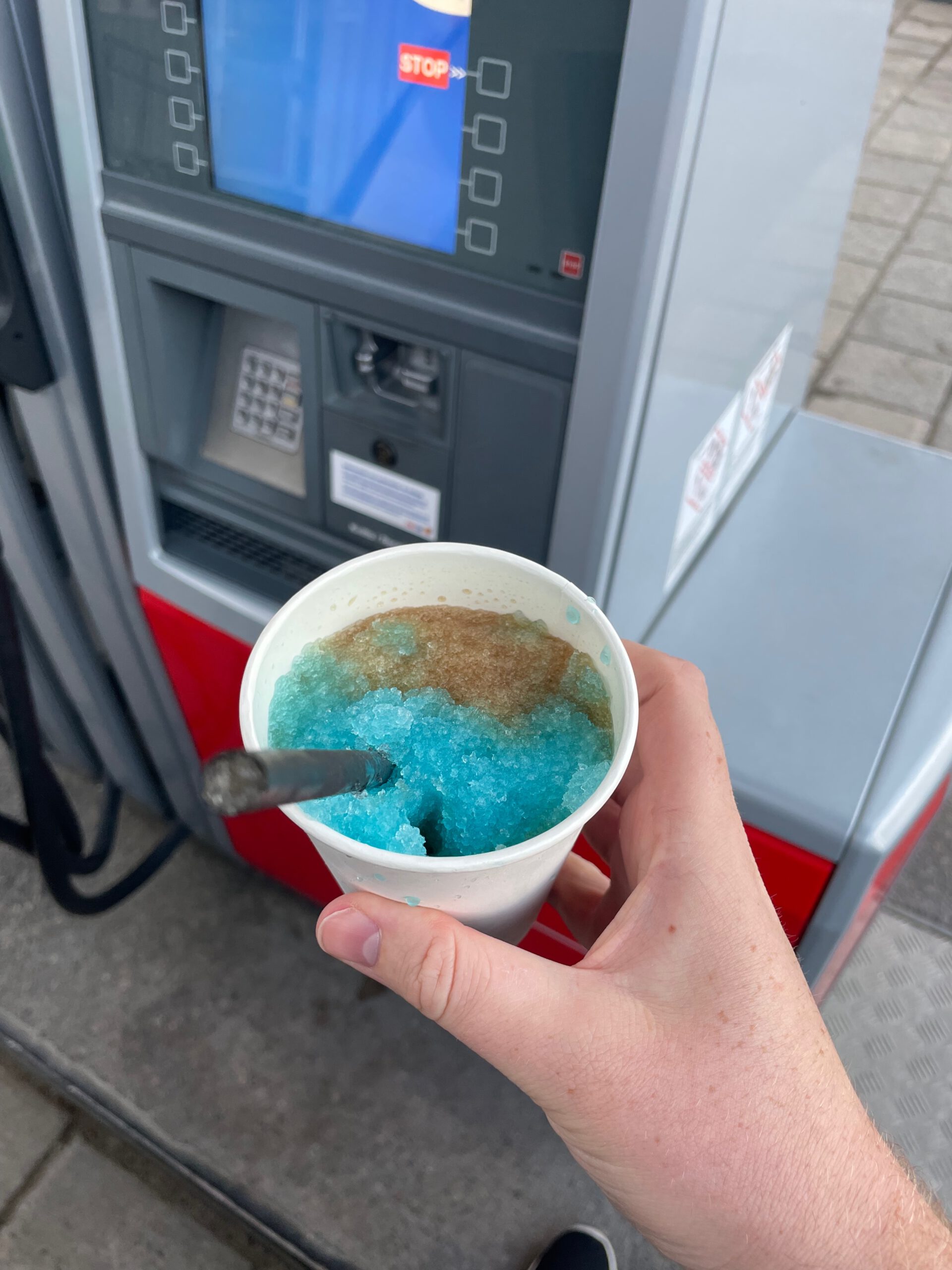 Blue slush drink from Töre KRUBB restaurant in Töre Sweden held during a road trip stop, highlighting a refreshing drink option for late evening travel