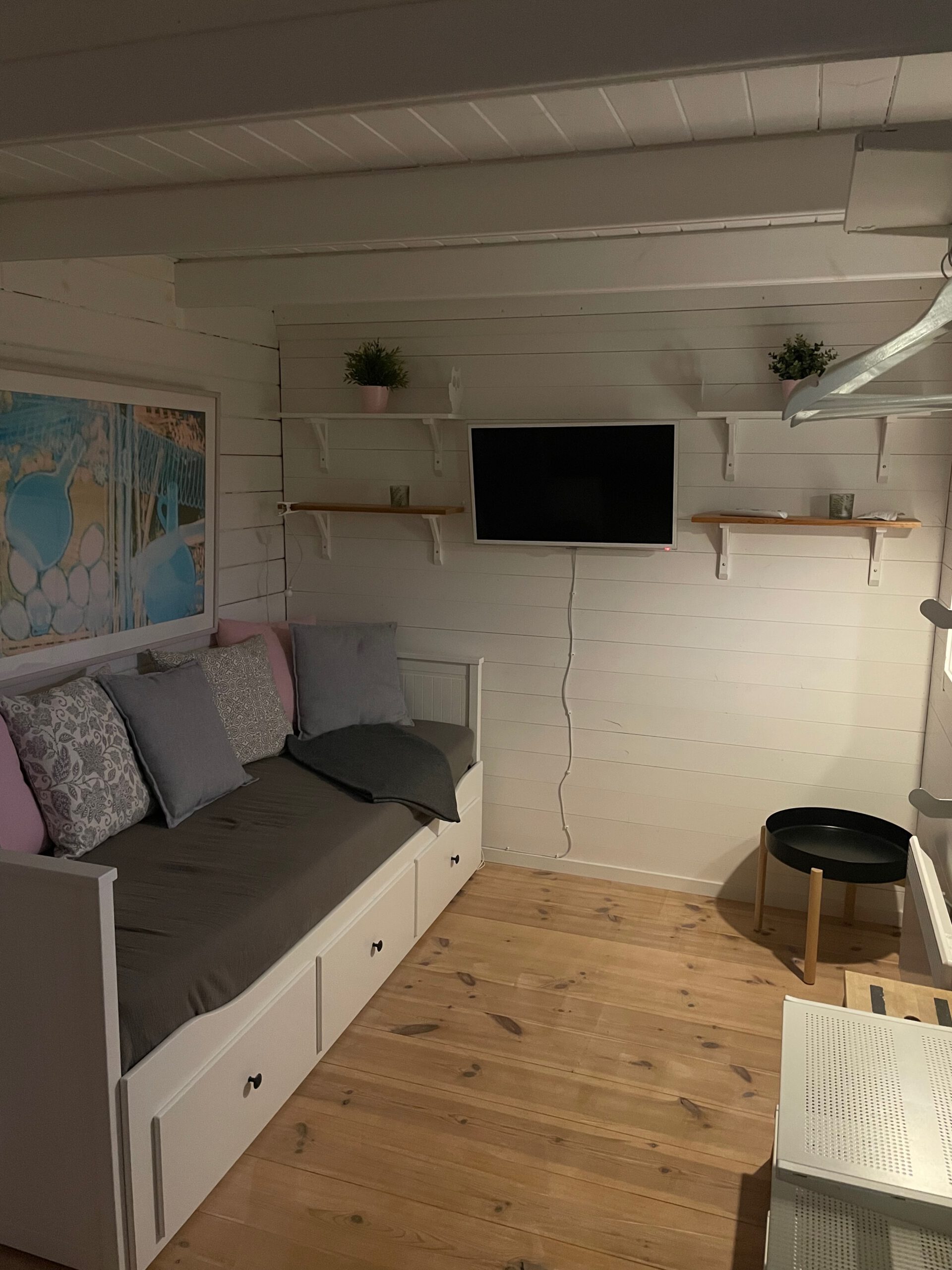 Cozy cottage with lake view Norra bergfors, cozy Airbnb living and sleeping area in Sweden with sofa bed, wooden floors, wall mounted TV and Scandinavian interior style