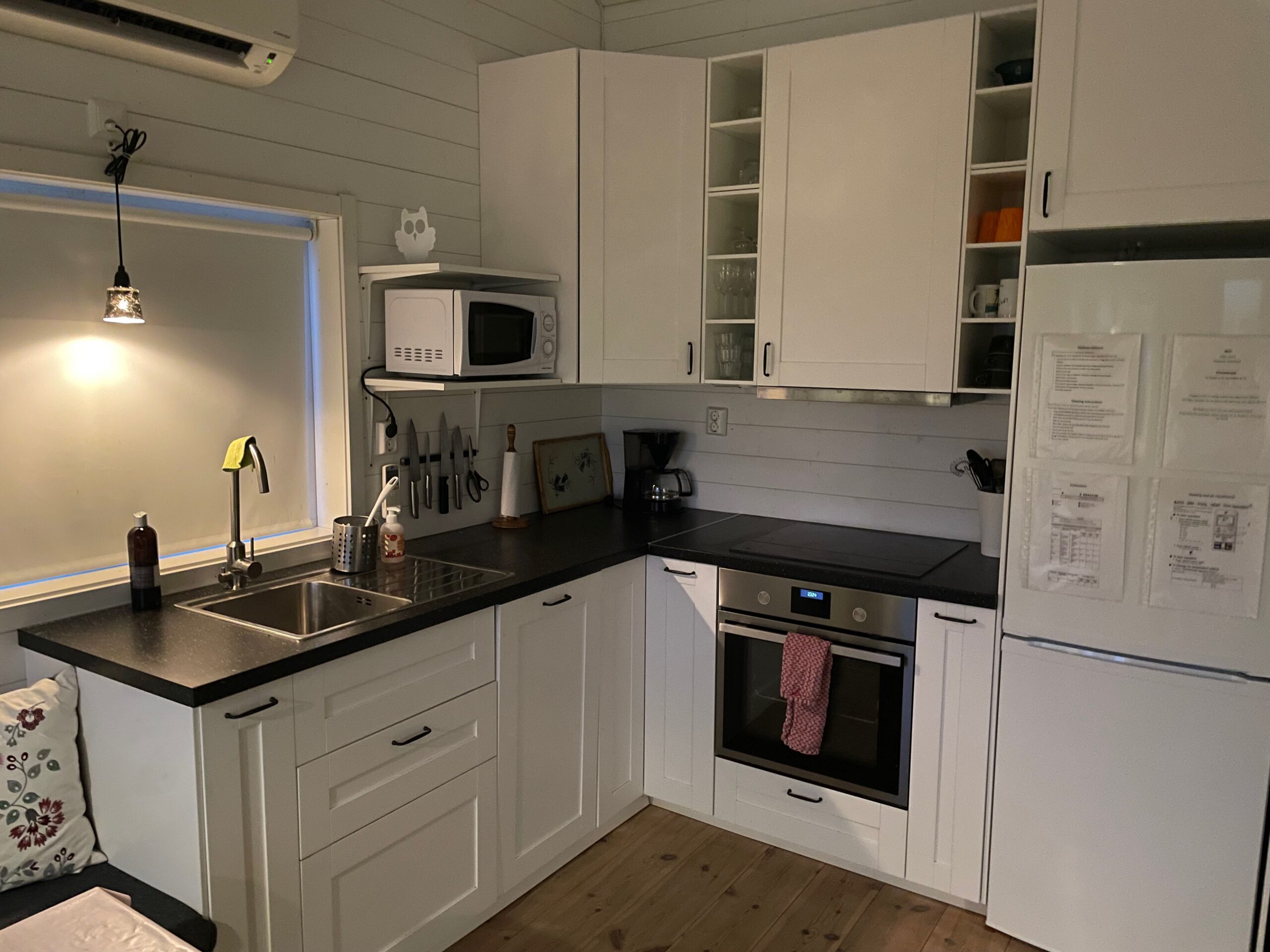 Cozy cottage with lake view Norra bergfors, modern white Airbnb kitchen in Sweden with oven, induction cooktop, microwave, refrigerator and fully equipped workspace