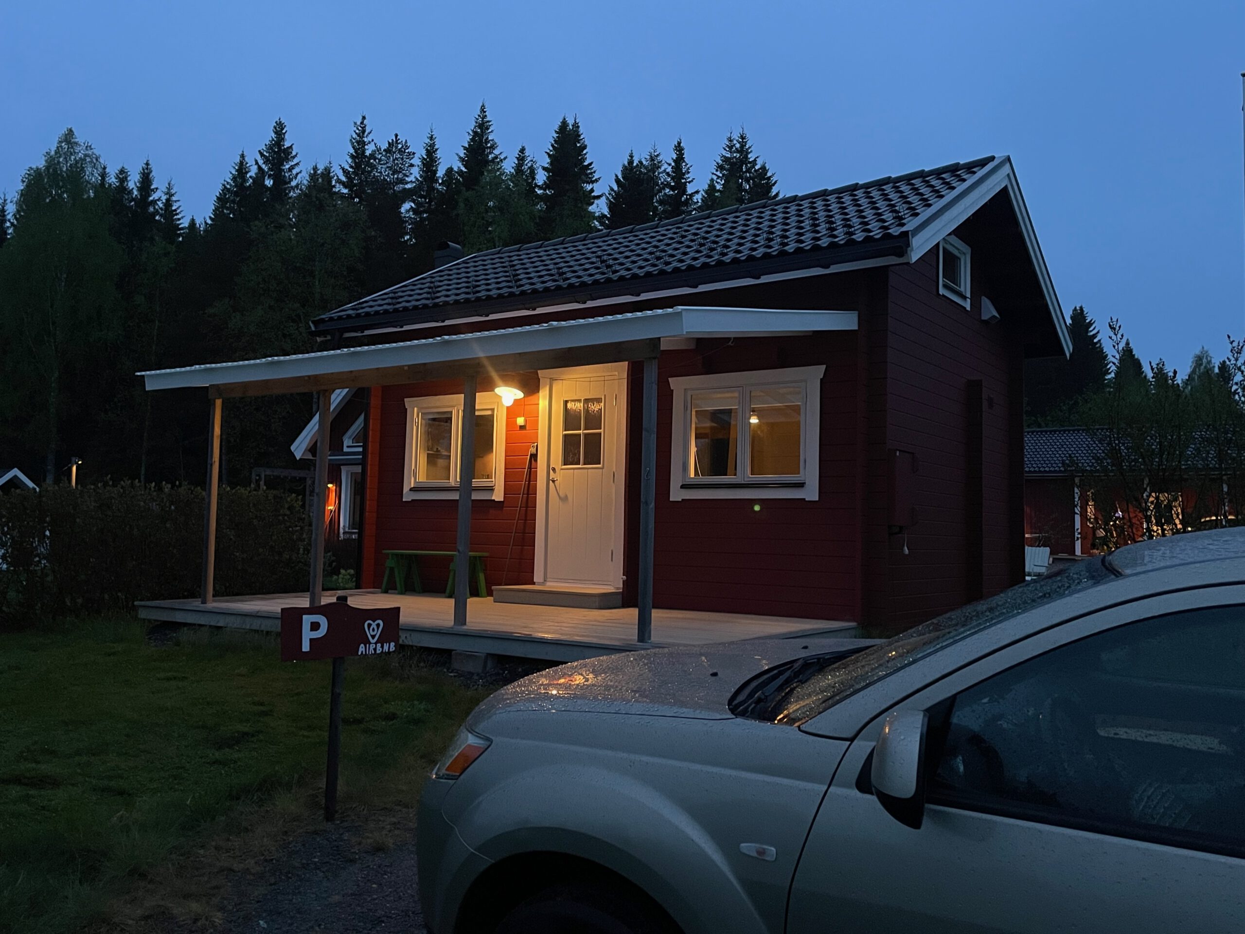 Cozy cottage with lake view Norra bergfors, red Swedish Airbnb cottage at dusk with warm interior lights, private parking and forest landscape