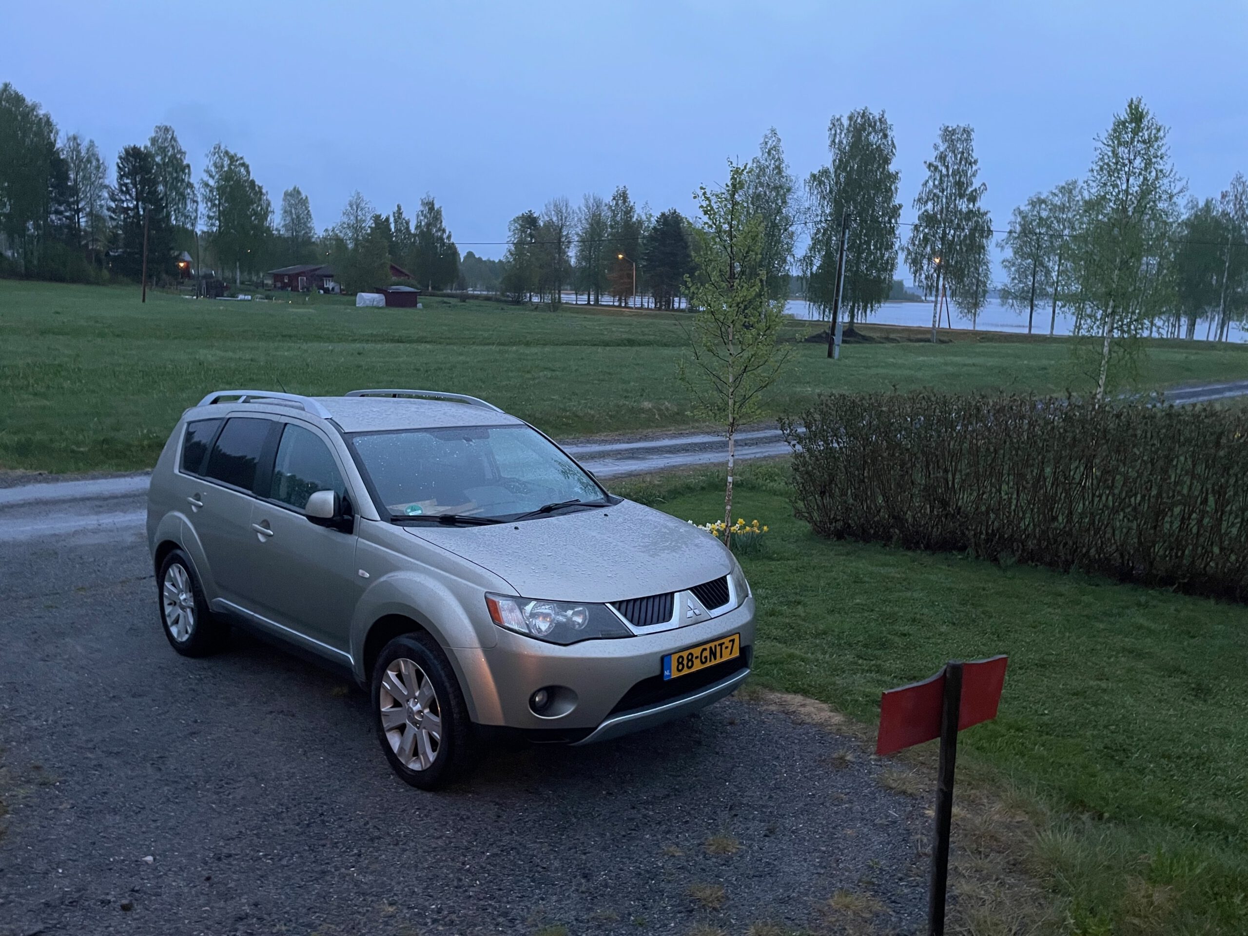Cozy cottage with lake view Norra bergfors, private Airbnb parking area at dusk with car parked near Lake Varuträsket and forest landscape