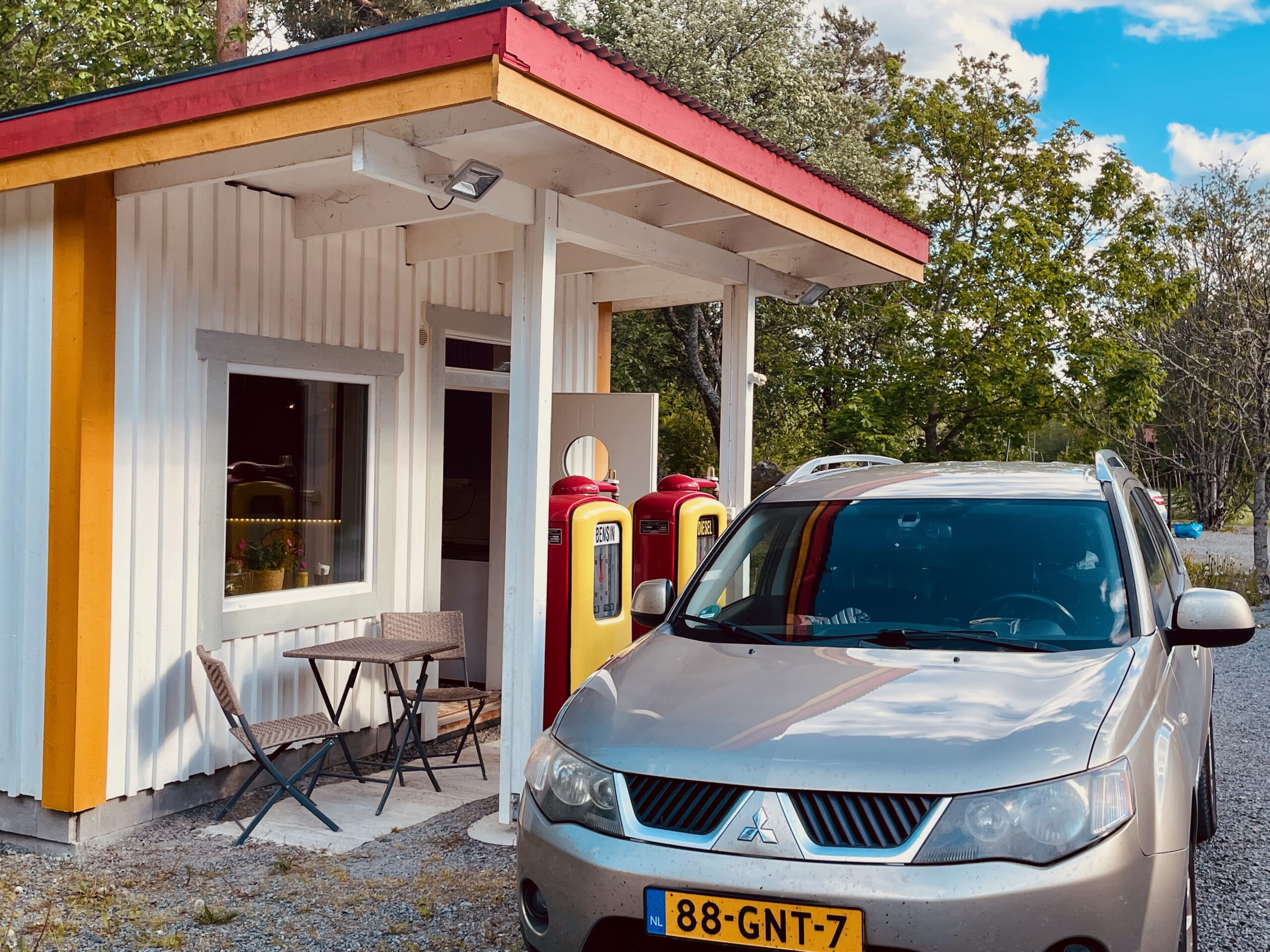 Shell Gas Station Airbnb Enkoping Sweden exterior with a vintage Shell gas station building, classic fuel pumps, parked car and rural Swedish countryside setting