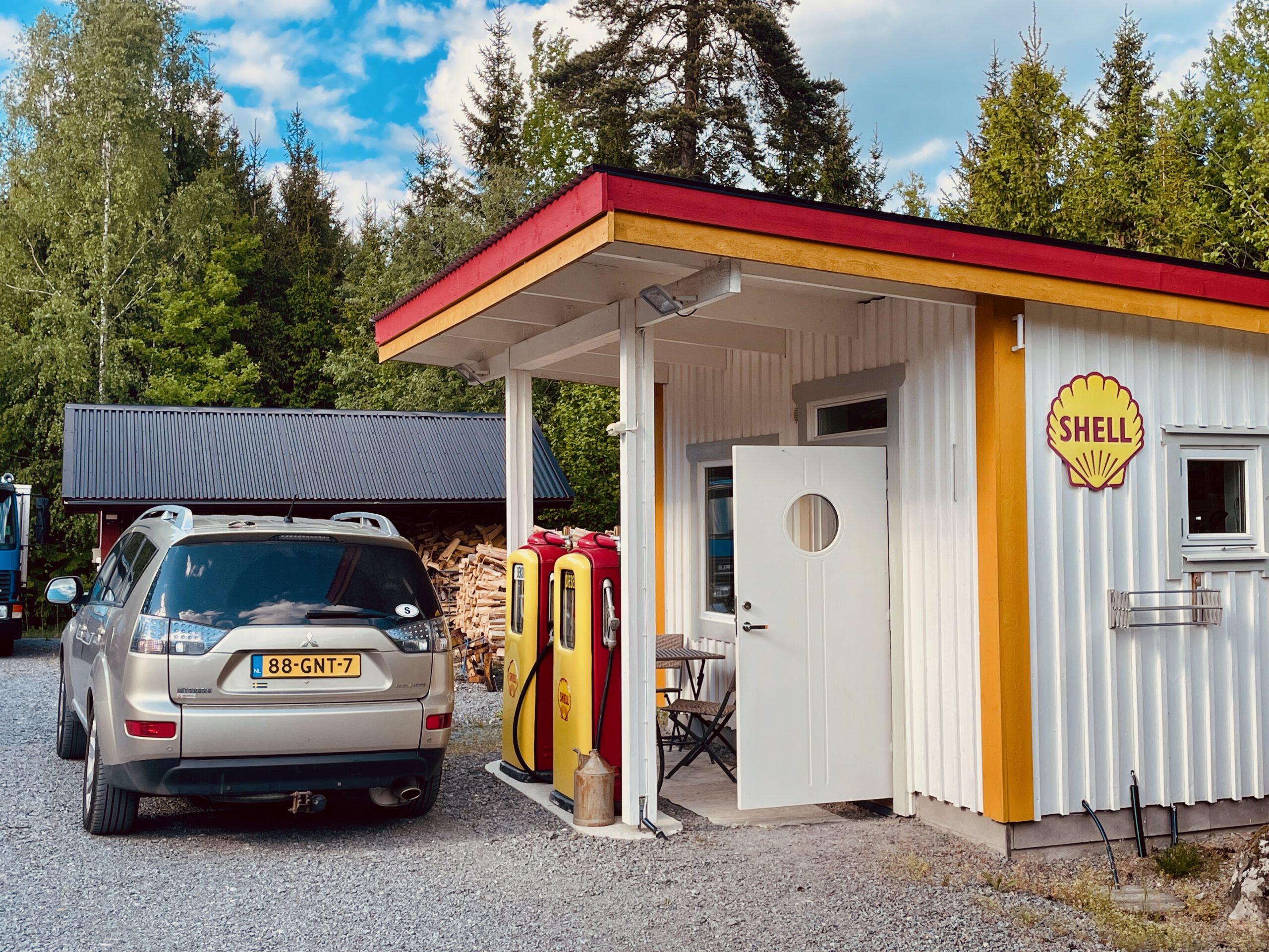 Shell Gas Station Airbnb Enkoping Sweden with a vintage Shell gas station building on a Swedish farm, featuring classic fuel pumps, nostalgic design and on site parking in a rural setting