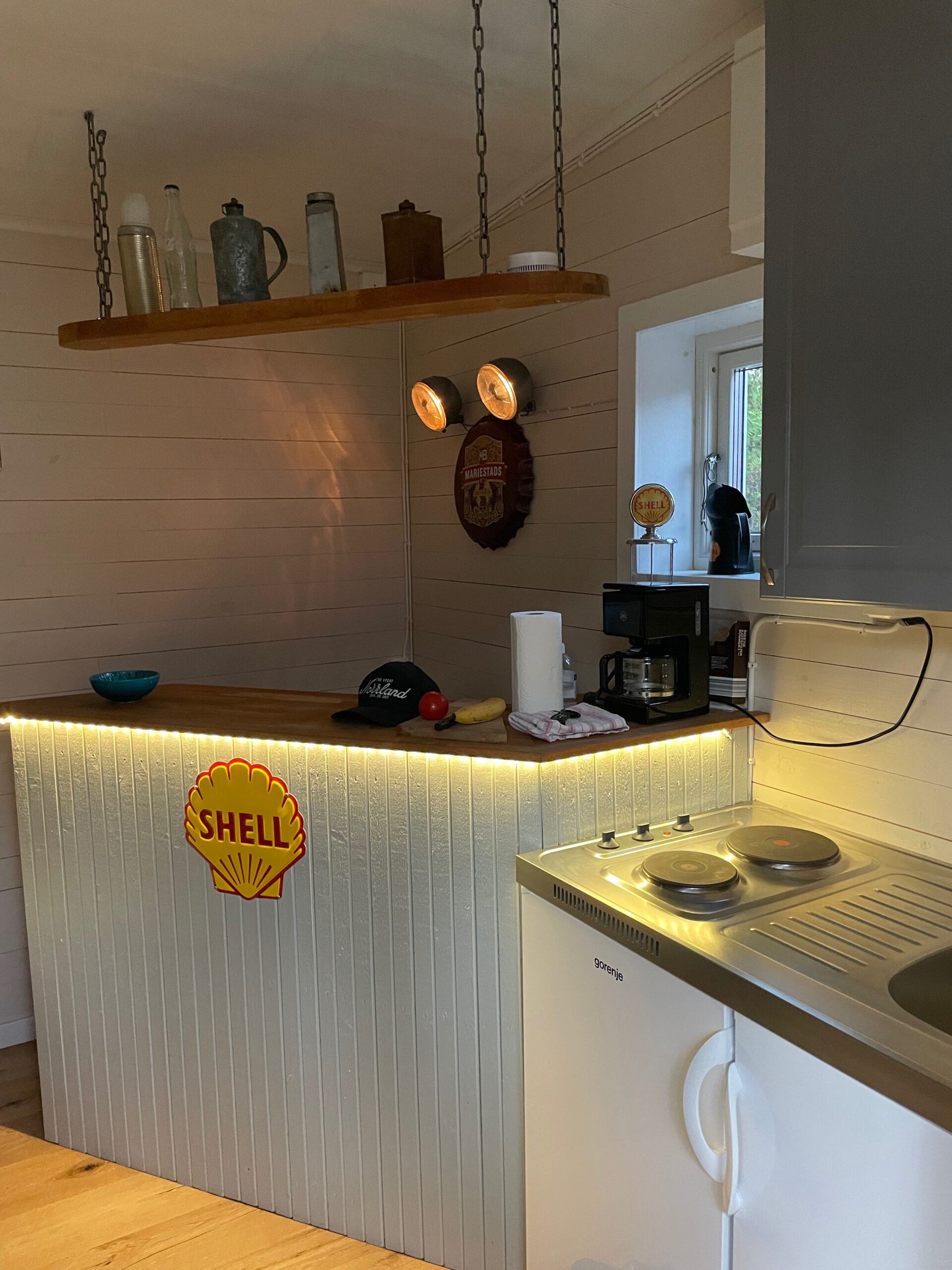 Shell Gas Station Airbnb Enkoping Sweden kitchen interior with vintage Shell bar, classic decor elements, basic cooking area and warm lighting inside the gas station Airbnb