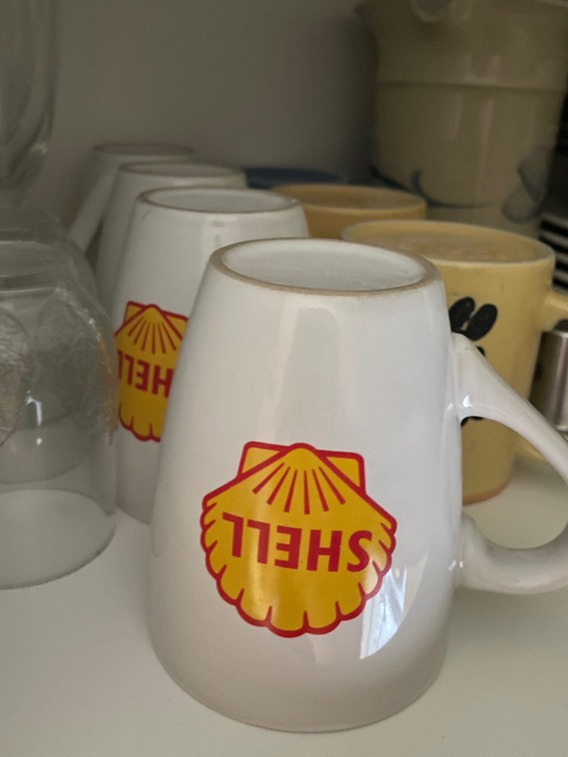 Shell Gas Station Airbnb Enkoping Sweden interior detail showing vintage Shell coffee mugs stored in the kitchen cupboard, emphasizing nostalgic gas station decor