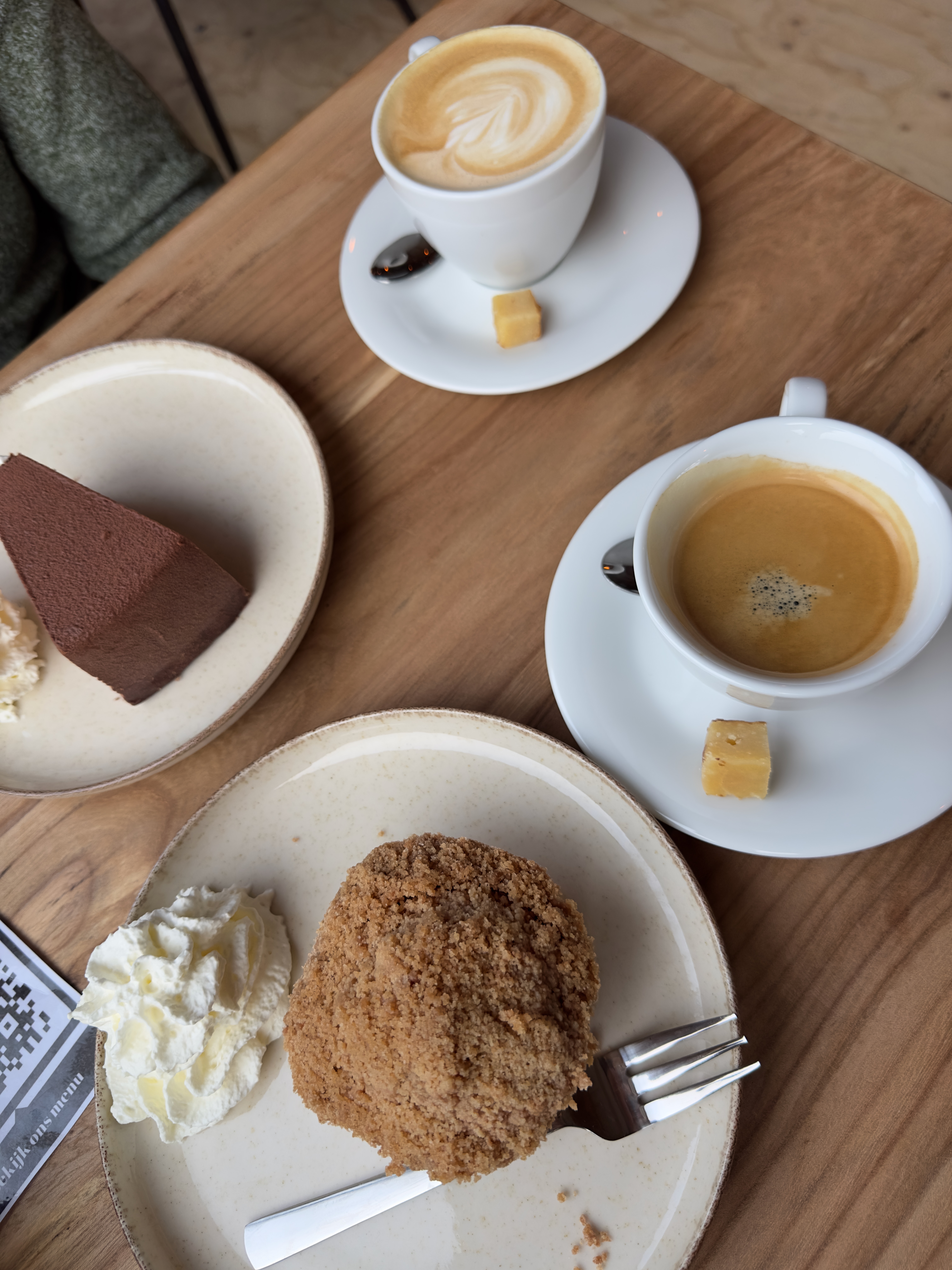 Coffee and pastries at BentGoud Bentwoud with cappuccino, espresso, apple cake, whipped cream, and chocolate dessert on a wooden table