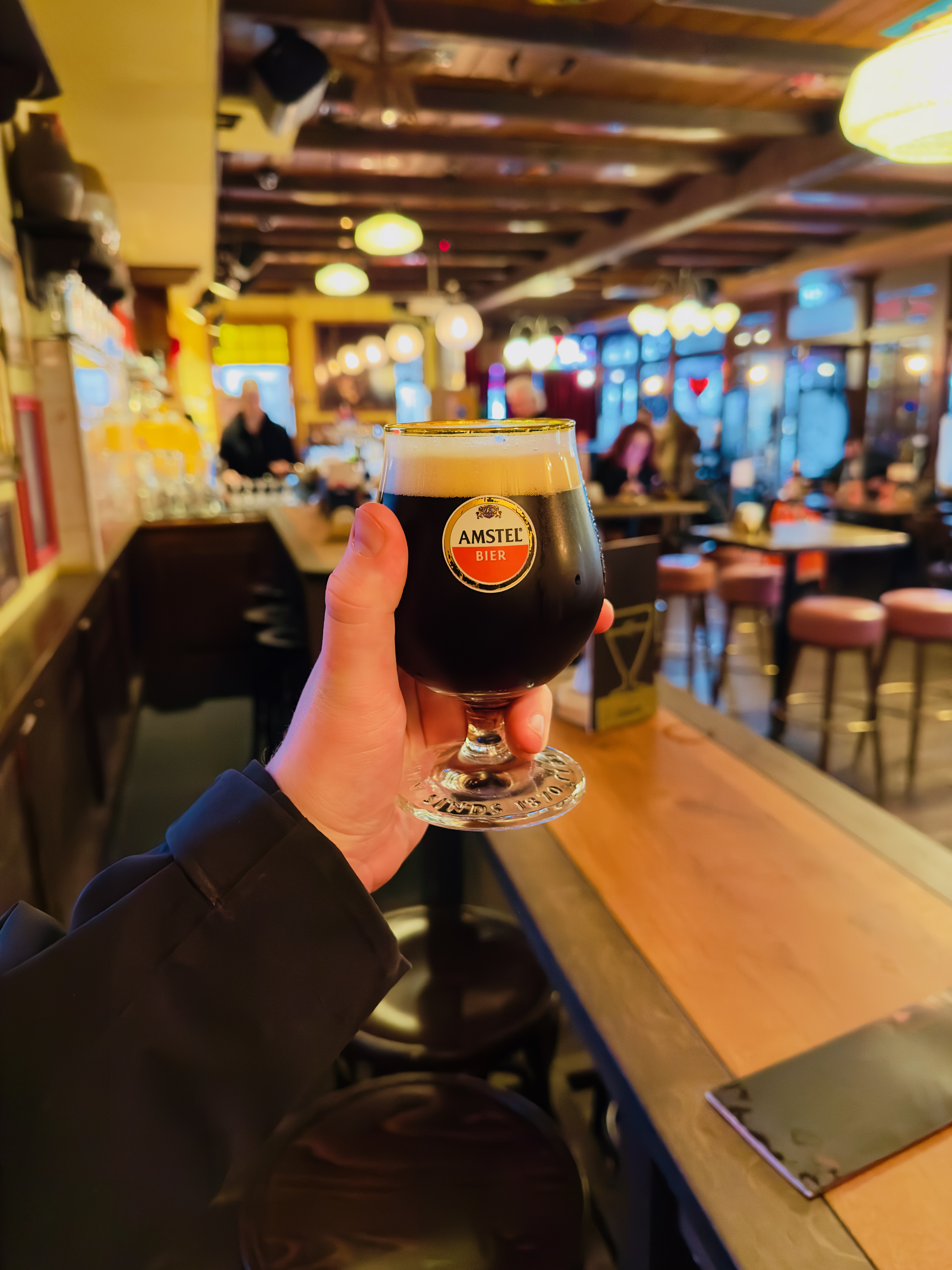 Café Rembrandt Schiphol interior with an Amstel Bock beer at the bar, showcasing the cozy brown café atmosphere at Schiphol Amsterdam Airport