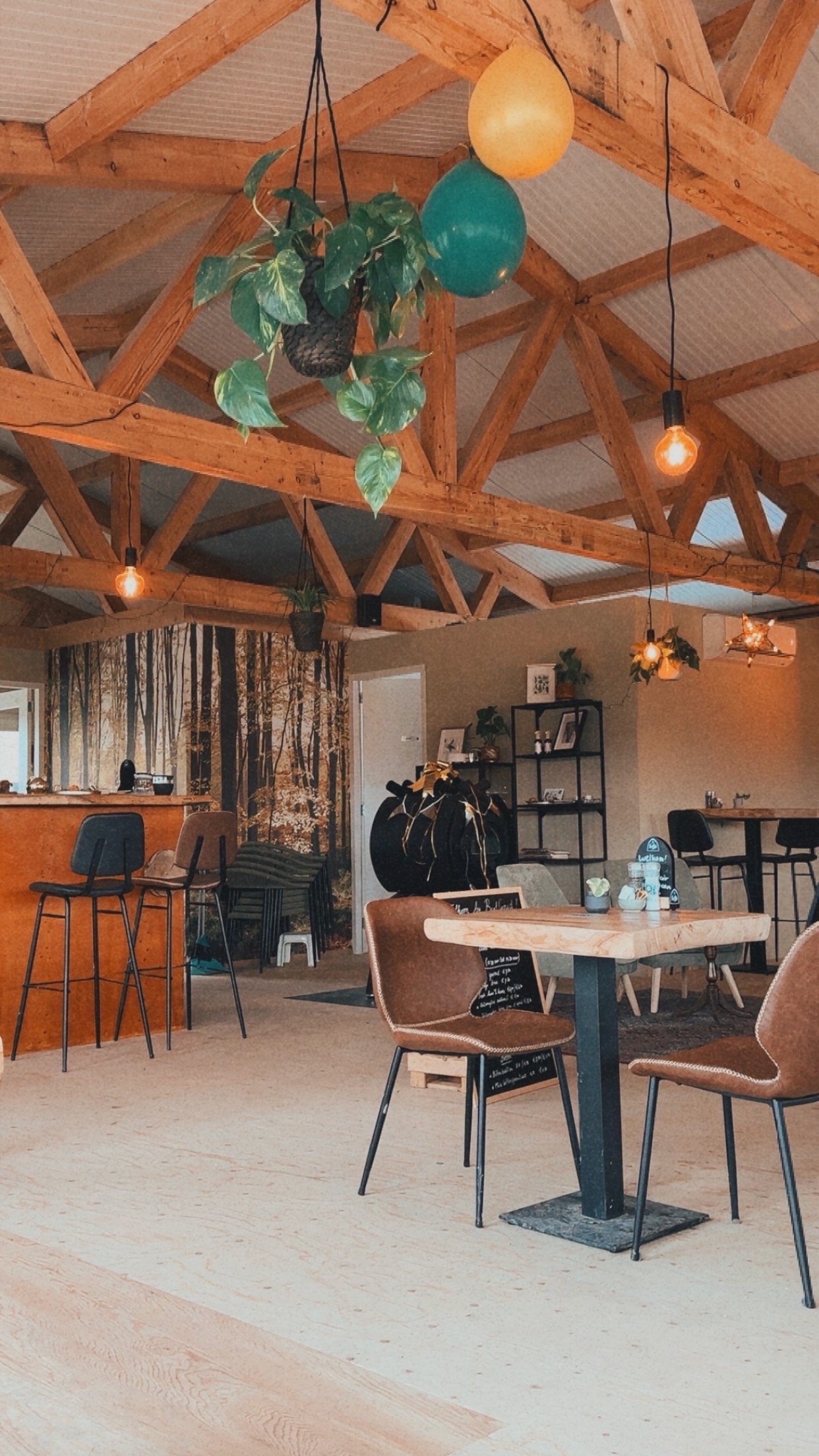 Interior of BentGoud Bentwoud with wooden beams, warm lighting, plants, and a cozy seating area inside the restaurant near the Bentwoud nature area
