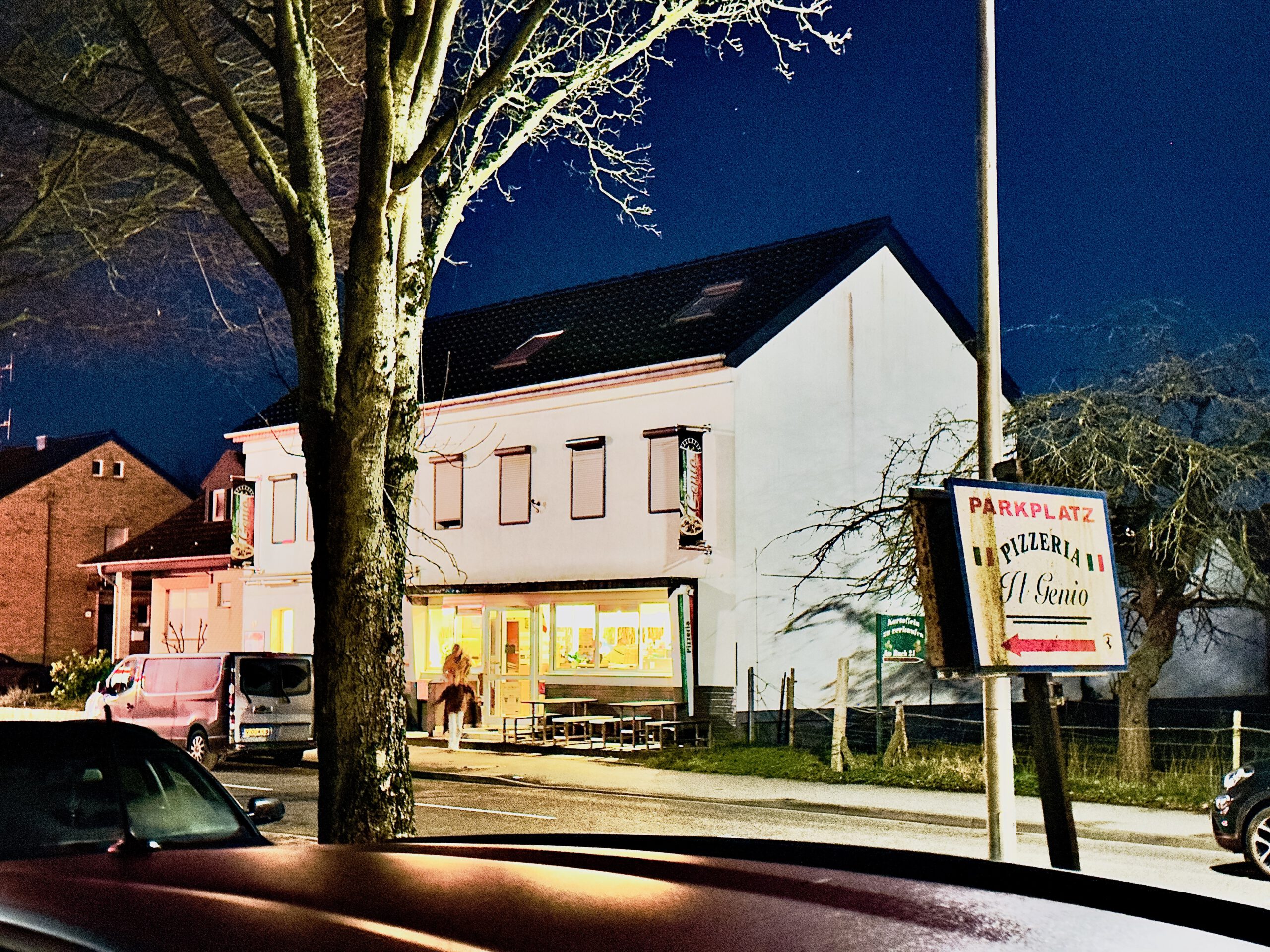 Pizzeria Il Genio Karken restaurant review cover image showing the exterior of Pizzeria Il Genio in Heinsberg Karken at night, with illuminated windows, parking sign, and a calm border town atmosphere.