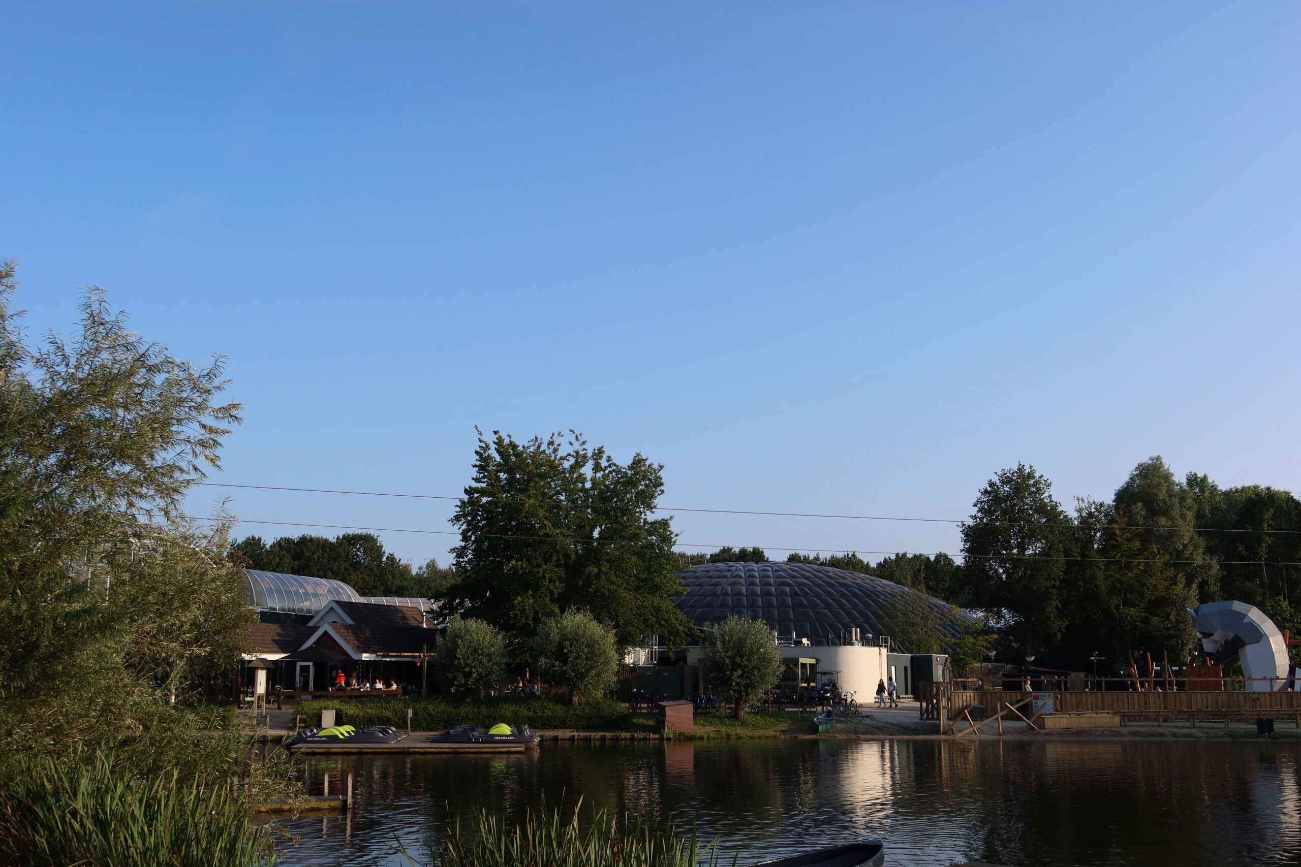 Center Parcs De Huttenheugte Day Visit lake view with the original dark brown Aqua Mundo dome and Market Dome buildings in Dalen, Drenthe during golden hour before renovation.