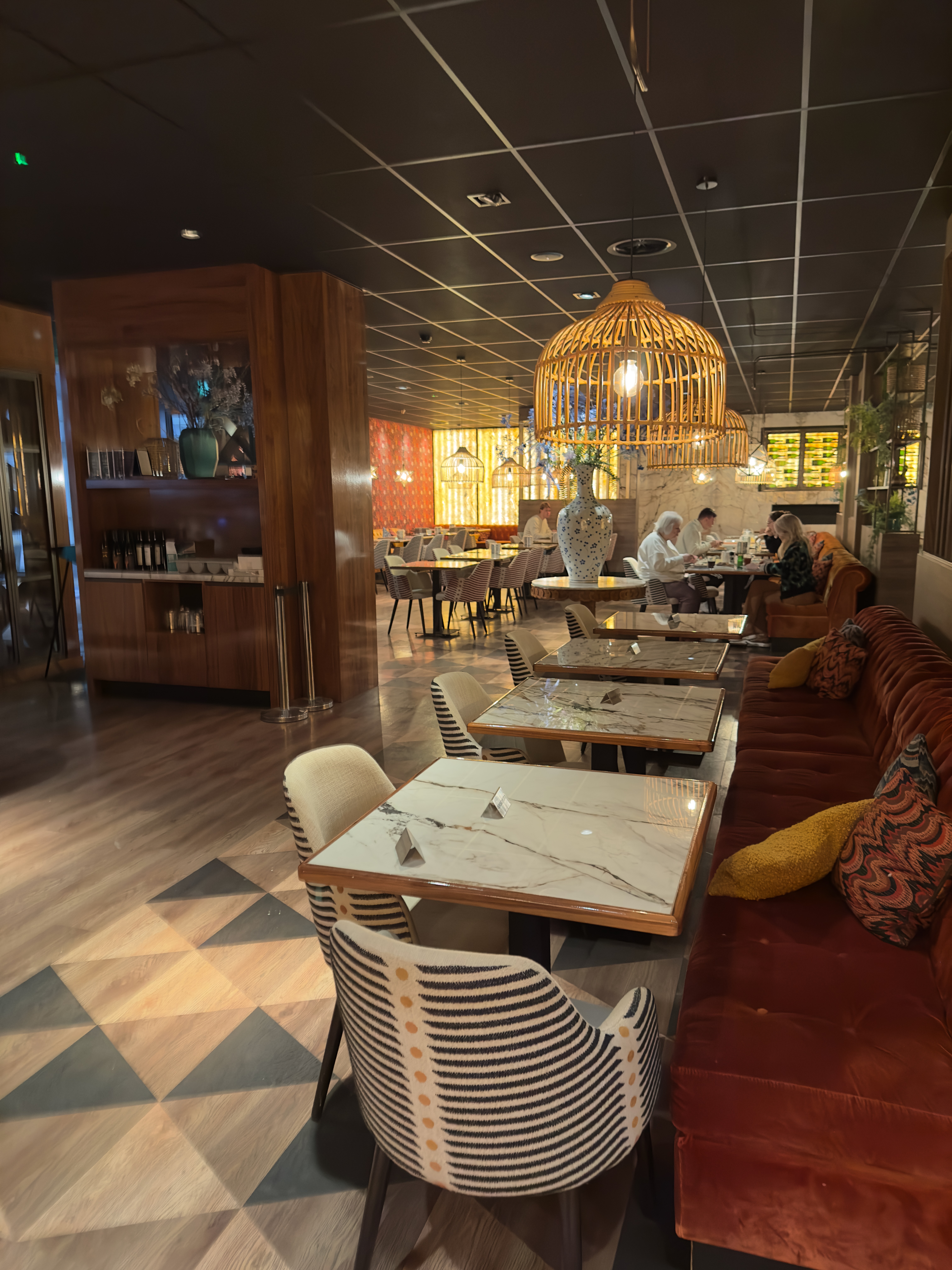 Grand Hotel Ter Duin review – modern restaurant interior with marble tables, velvet seating, warm wooden accents, woven pendant lights and cozy dining atmosphere in Burgh-Haamstede.