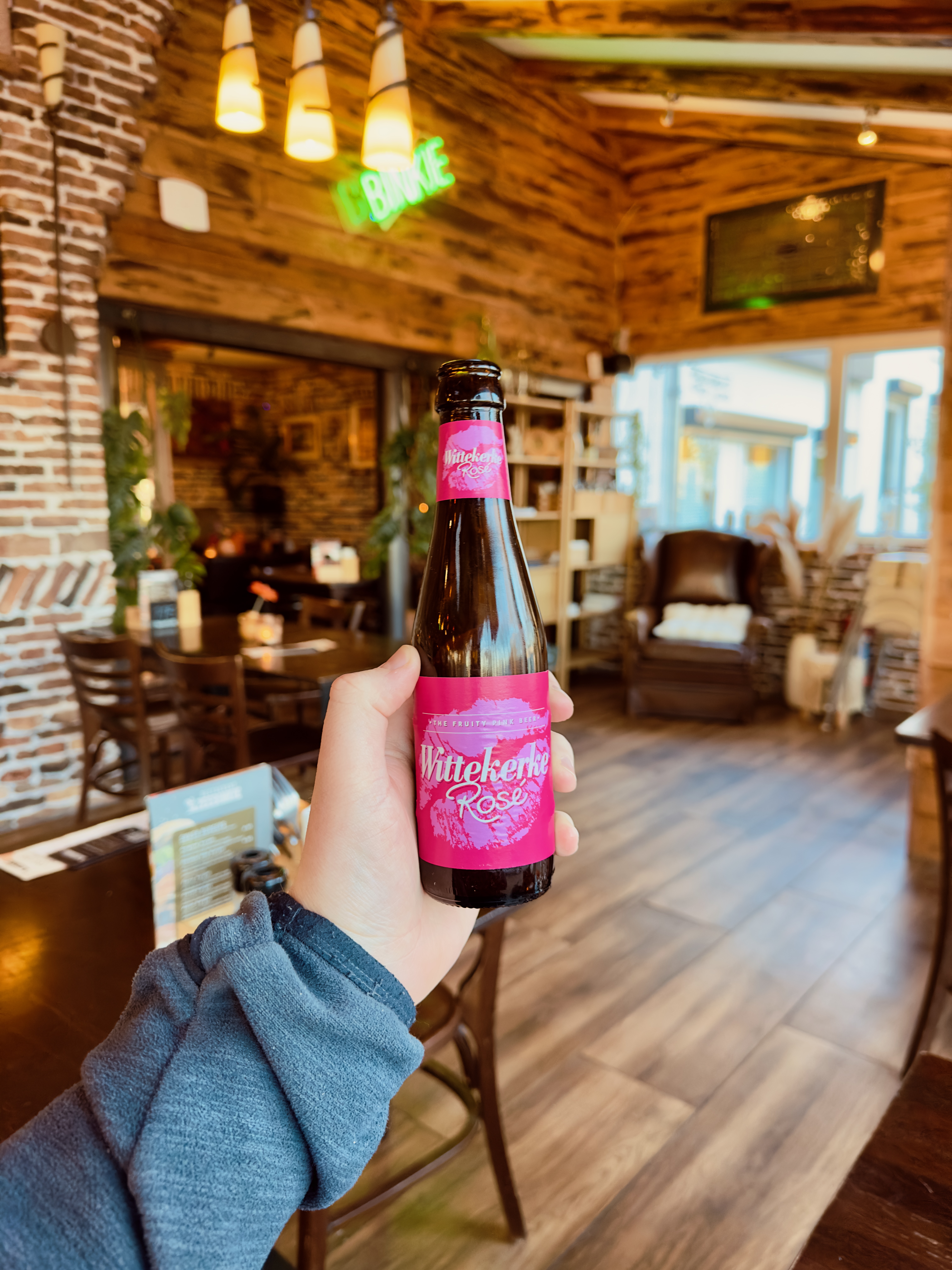 Restaurant Zeebinkie review, bottle of Wittekerke Rosé fruit beer from Brouwerij De Brabandere inside Restaurant Zeebinkie in Burgh Haamstede with warm wooden interior and fireplace setting