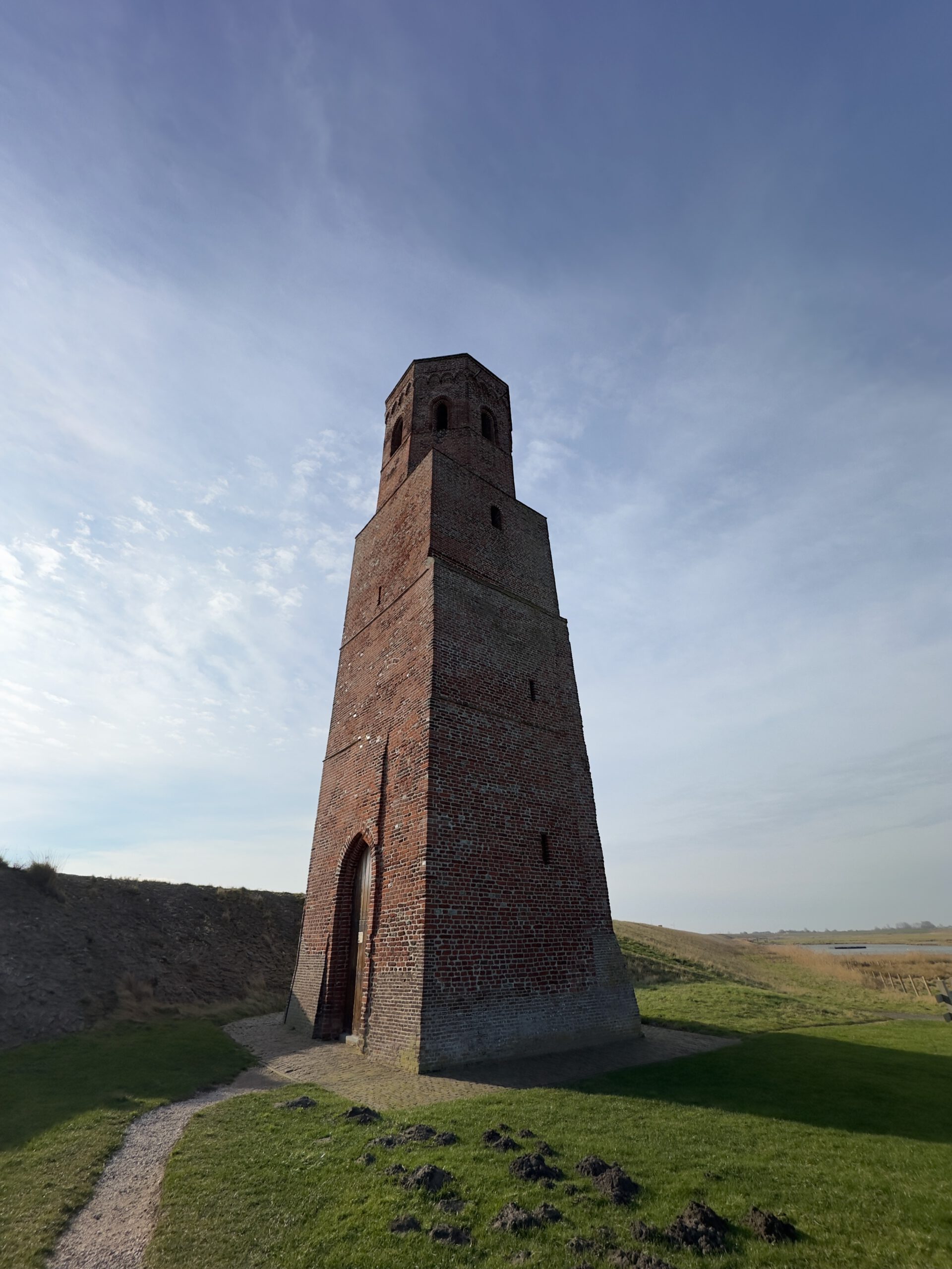 Plompe Toren Koudekerke low angle view of the historic 23 meter brick tower along the Oosterschelde dike in Zeeland under wide blue sky
