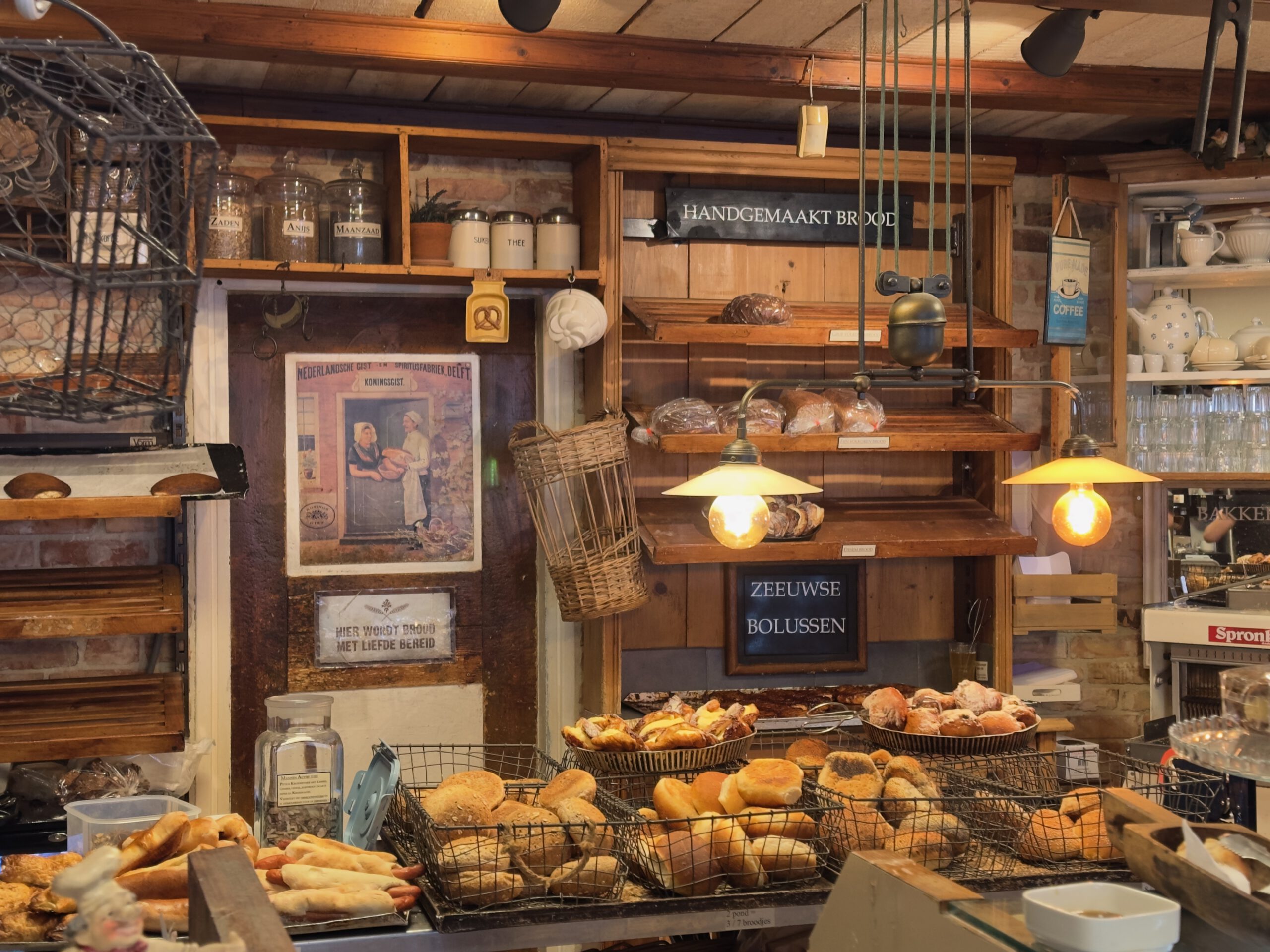 Bakkerij Sonnemans in Burgh Haamstede interior with Zeeuwse bolussen, fresh bread baskets, vintage wooden shelves and warm hanging lights above the counter