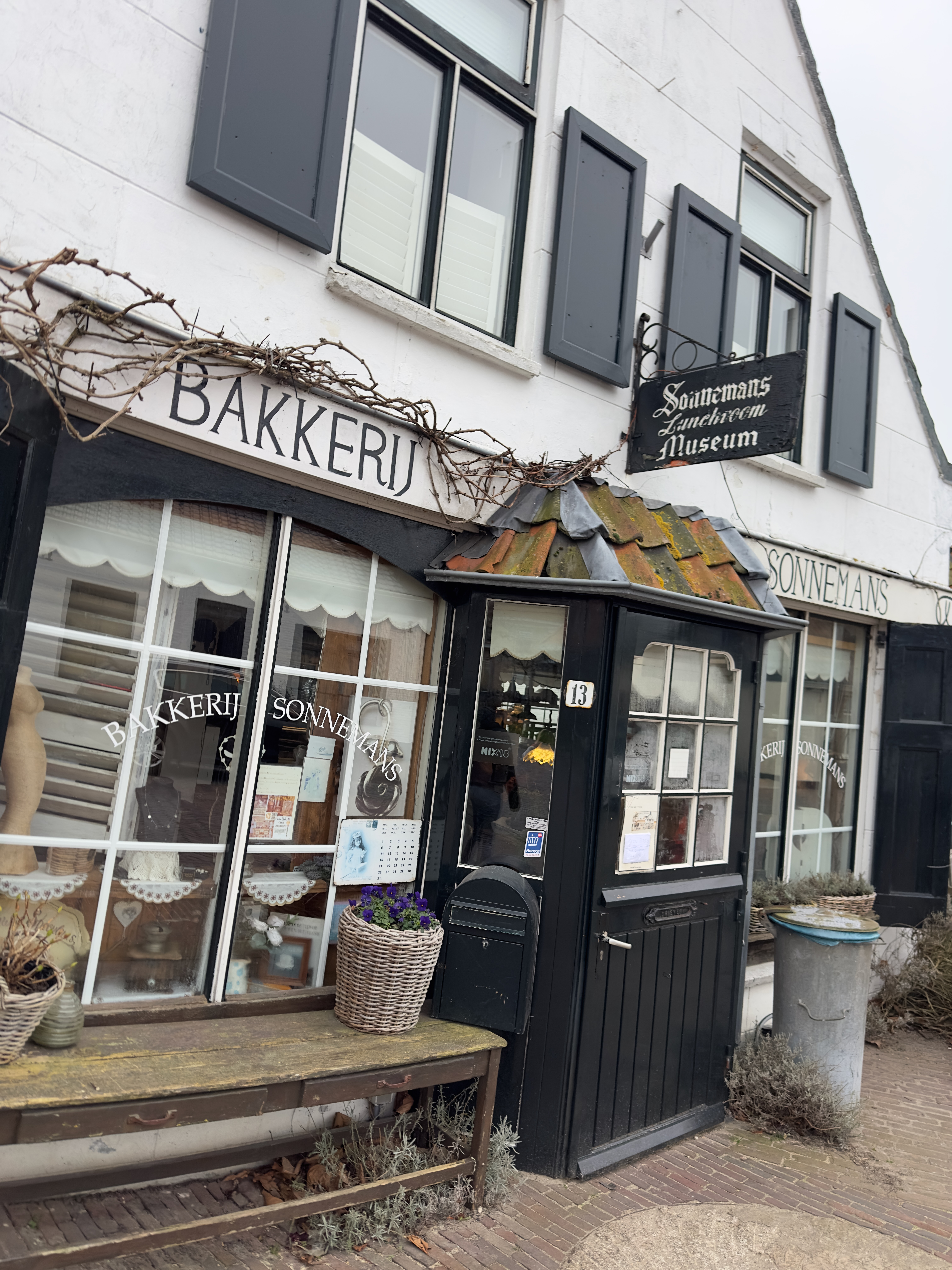 Bakkerij Sonnemans in Burgh Haamstede, traditional white facade with black shutters, rustic entrance at Hogeweg 13, vintage bakery sign and Sonnemans Zinckenoom Museum board above the door