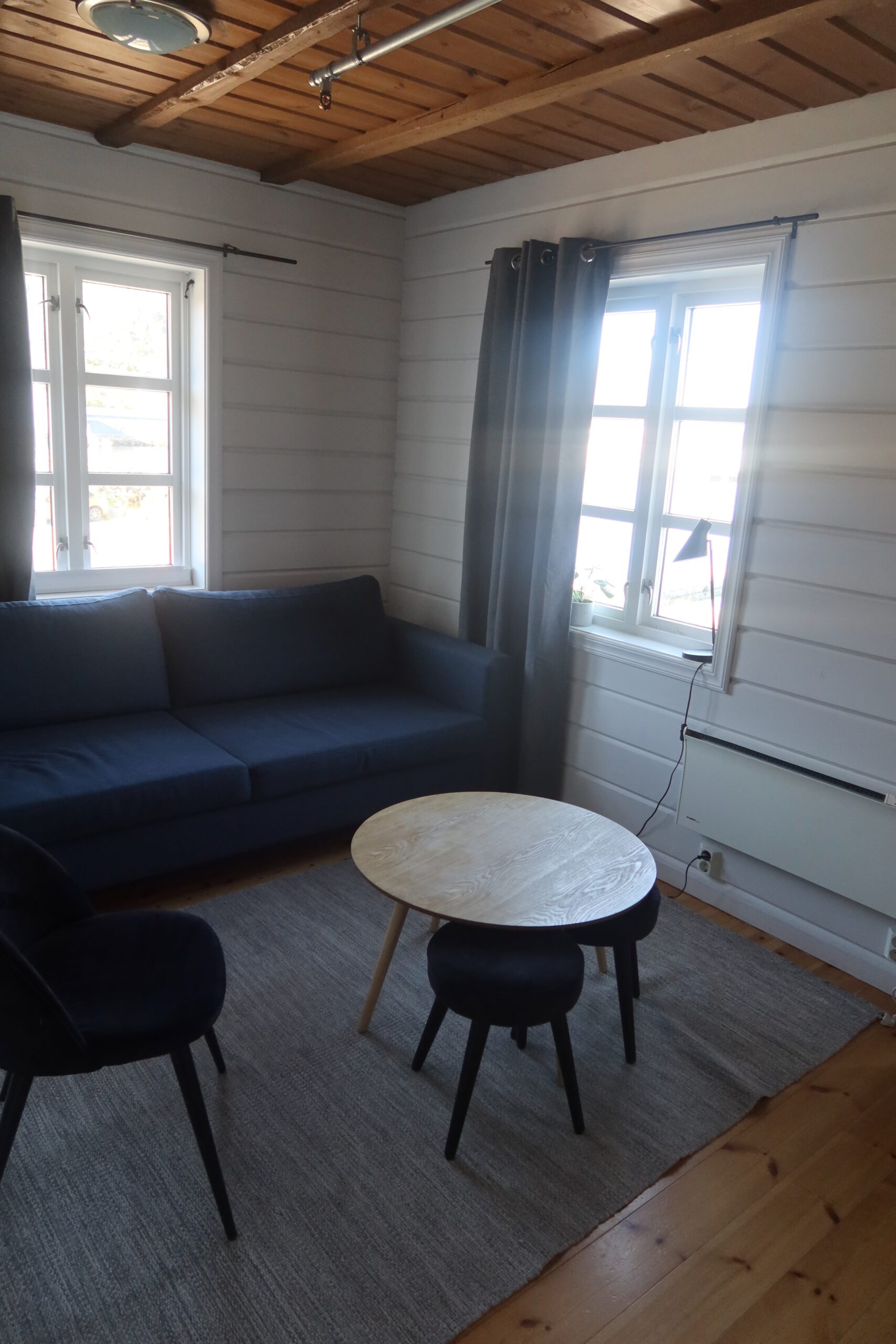Cozy living room with sofa and wooden ceiling at Lødingen waterfront hotel Norway, comfortable seating area inside a Norwegian coastal hotel room