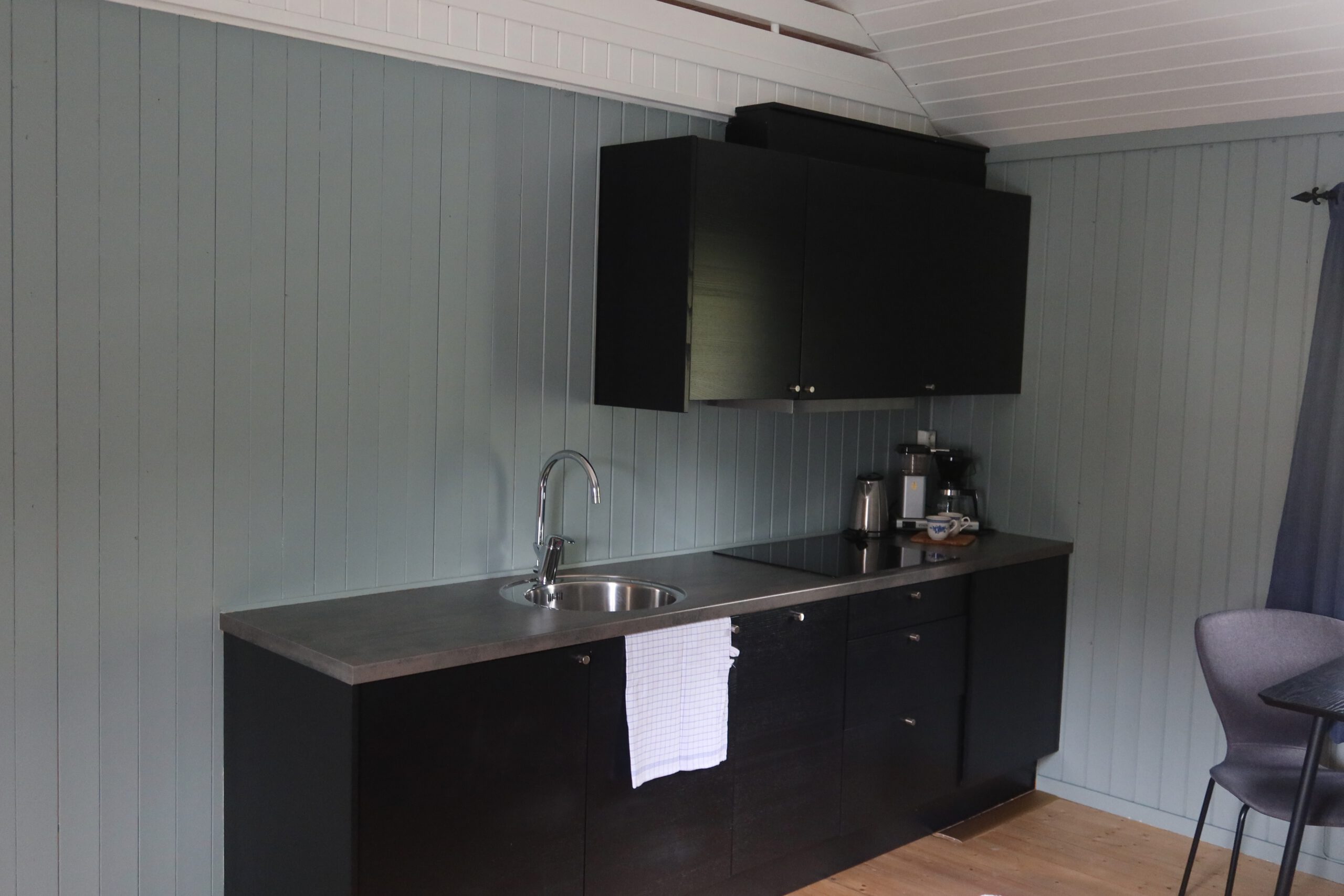 The Tide Lofoten fisherman cabins modern kitchenette with black cabinets, sink and coffee facilities inside the traditional fishing cabin
