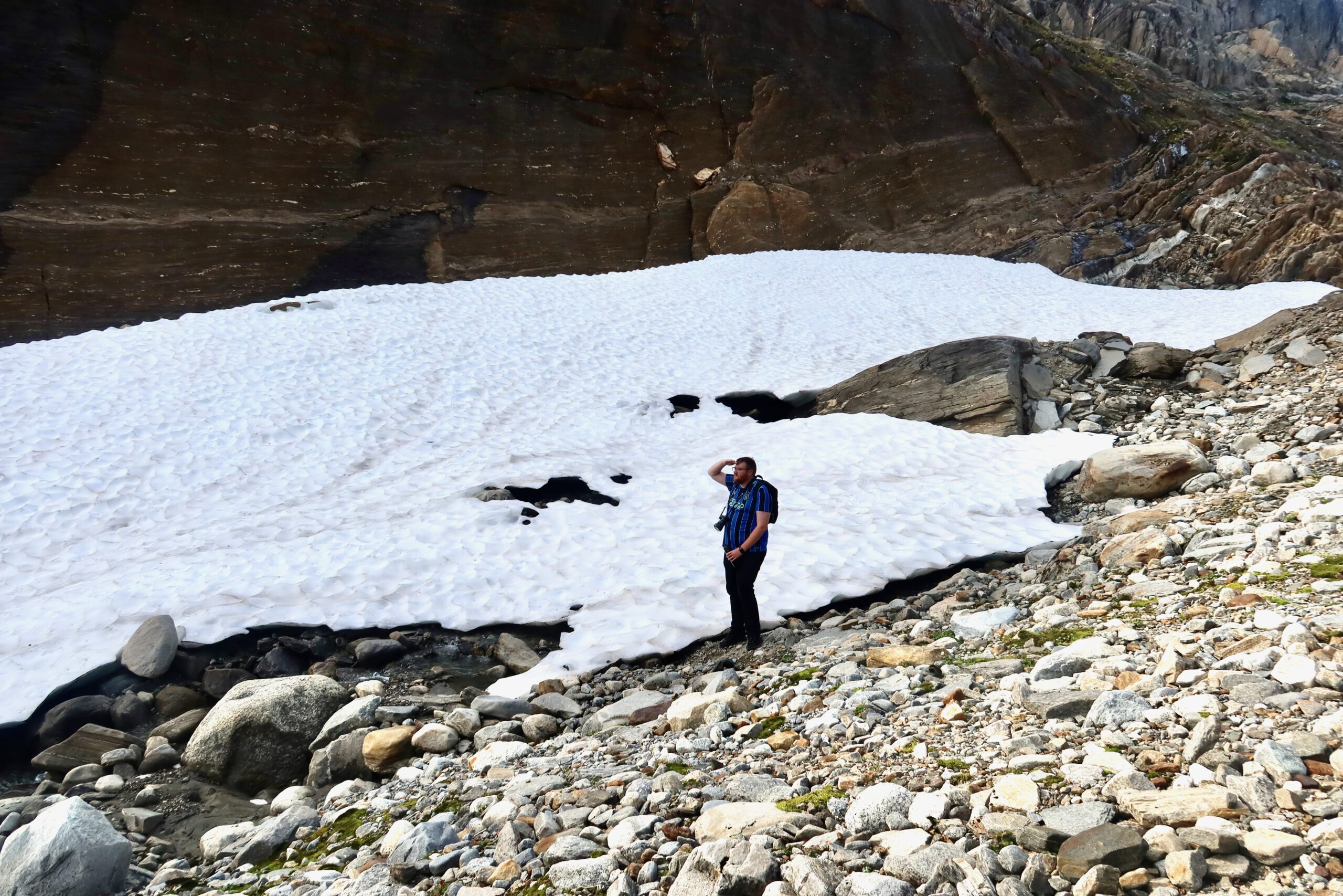 Glomfjord lake and dam adventure with Timo van den Berg, Timeuw, standing near a snowfield and rocky terrain close to Storglomvatnet during a hike in Northern Norway