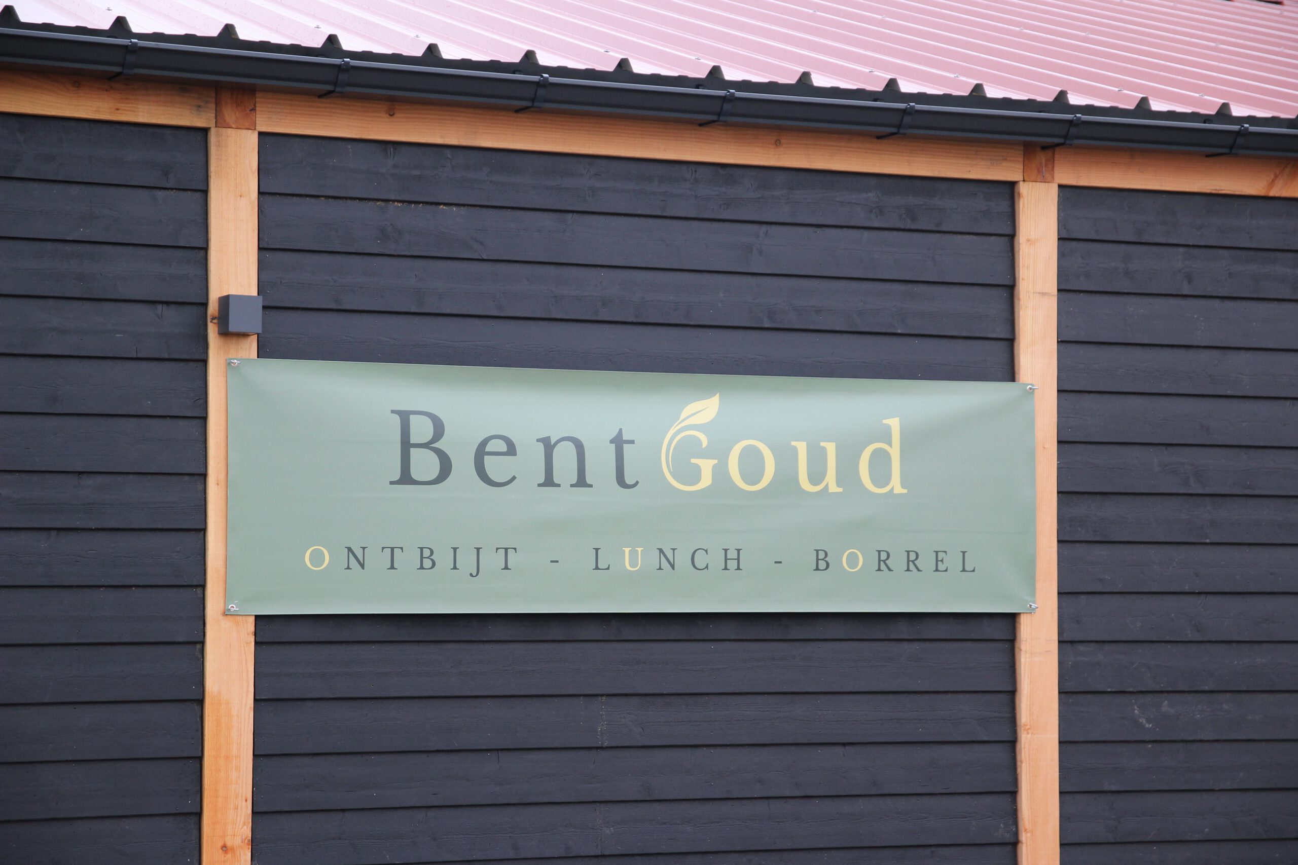 Exterior sign of BentGoud Bentwoud showing the restaurant name and breakfast, lunch, and drinks concept on the wooden building near the Bentwoud