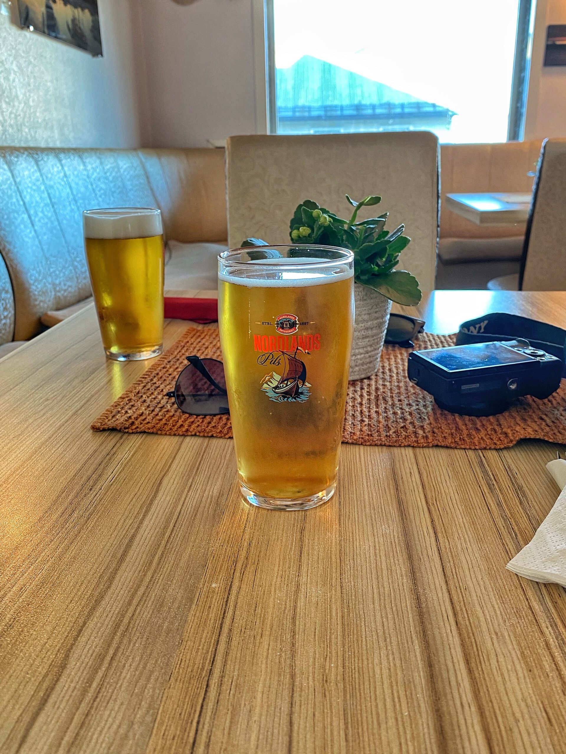 Mama Rosa Lødingen serving local Nordlands Pils beer at a wooden table inside the cozy pizza and grill restaurant