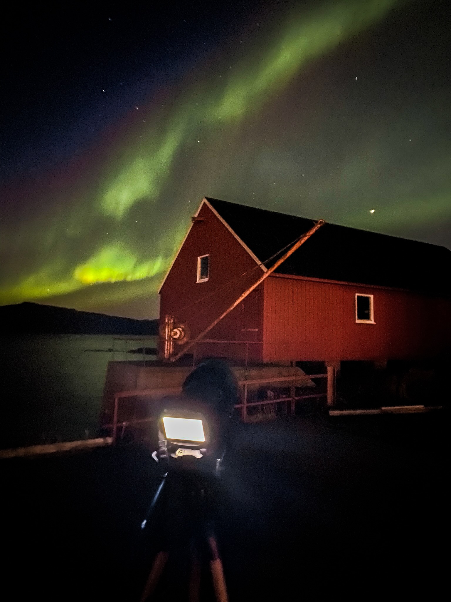 Hjertholmen Lødingen Northern Lights photographed with a Sony A6300 and Sony E 18–105mm lens, showing green aurora above a red coastal boathouse at night
