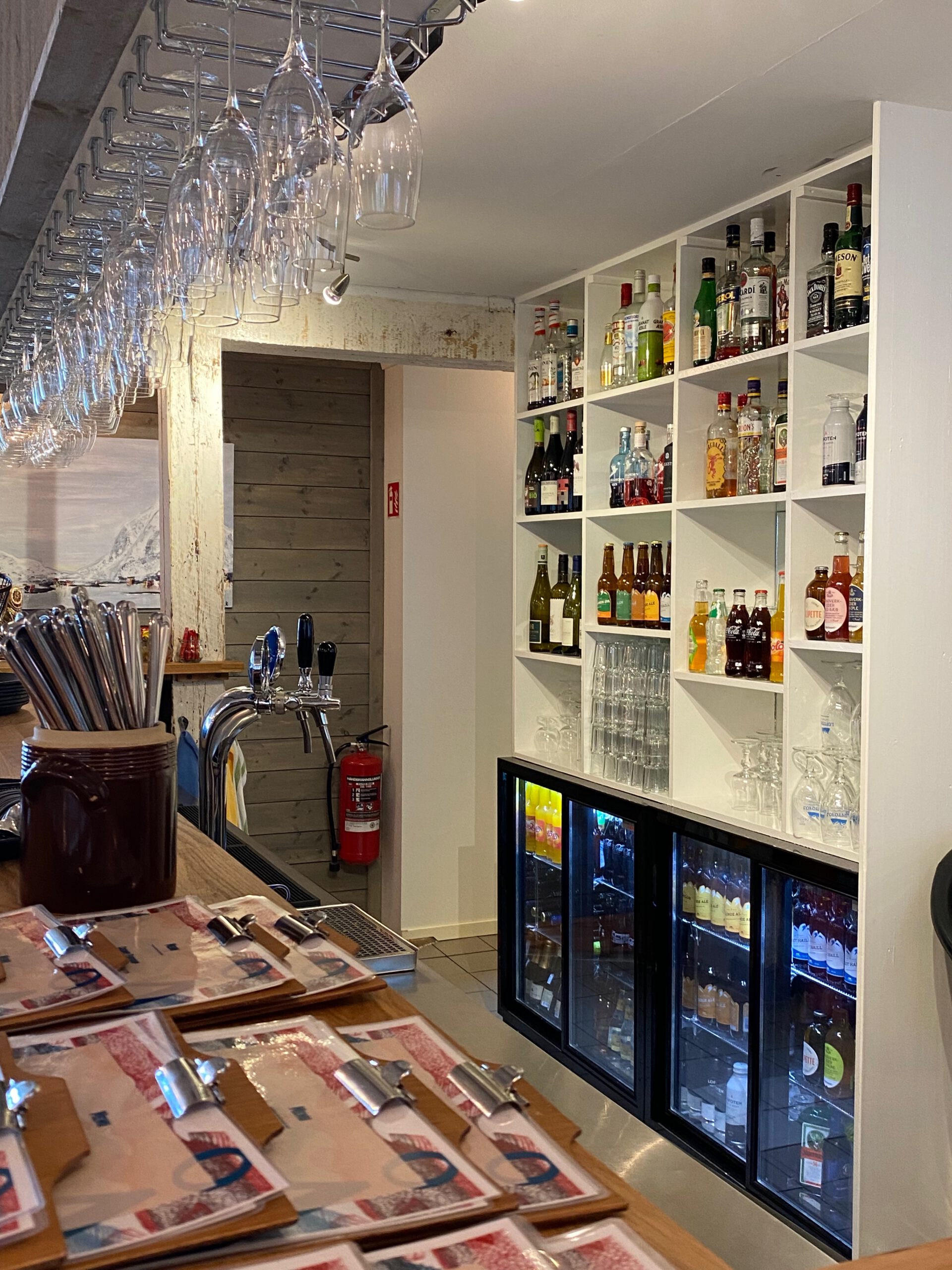 Å Rorbuer Lofoten restaurant interior showing the bar with hanging glasses and a wide selection of beers and spirits in Å i Lofoten Norway