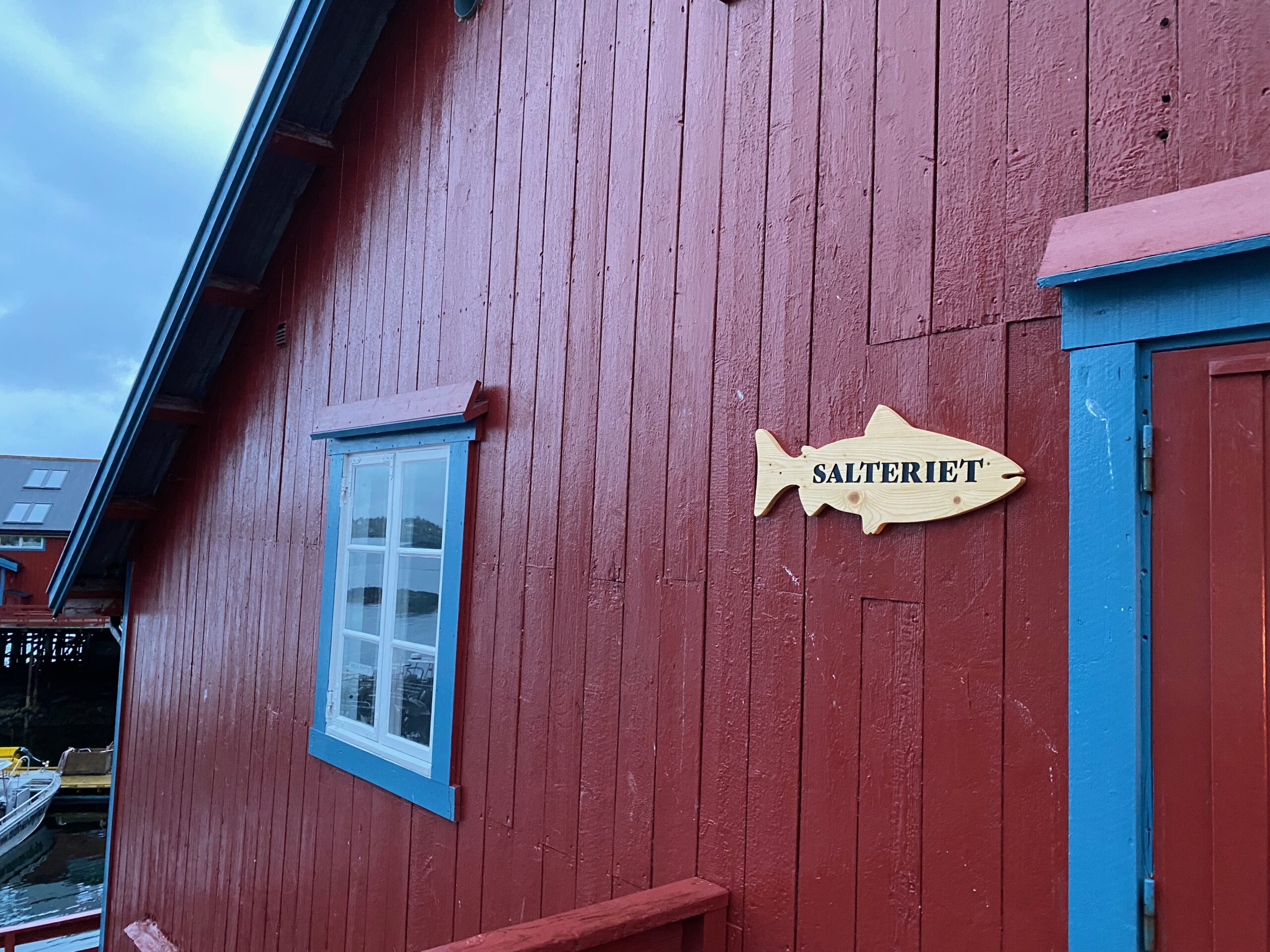 Å Rorbuer Lofoten Salteriet fishing cabin exterior with wooden fish sign and blue trimmed windows in Å i Lofoten Norway
