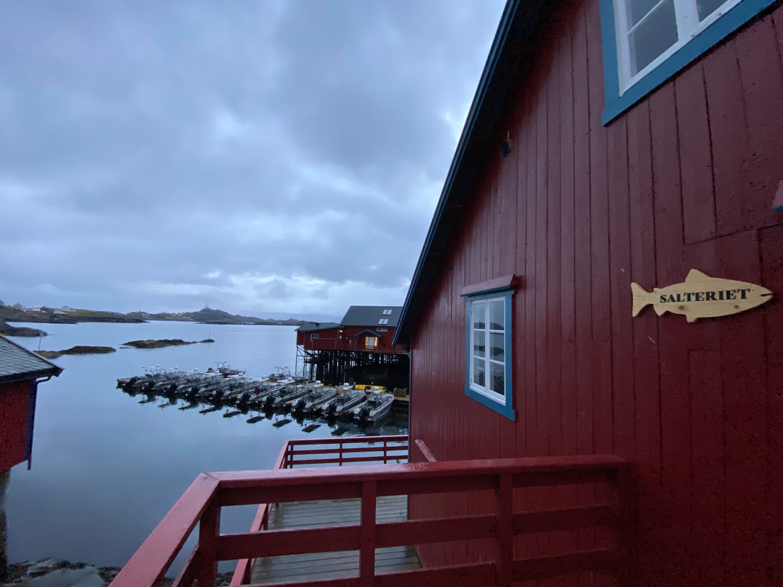 Å Rorbuer Lofoten red fishing cabin Salteriet overlooking the harbor and moored fishing boats at dawn in Å i Lofoten Norway