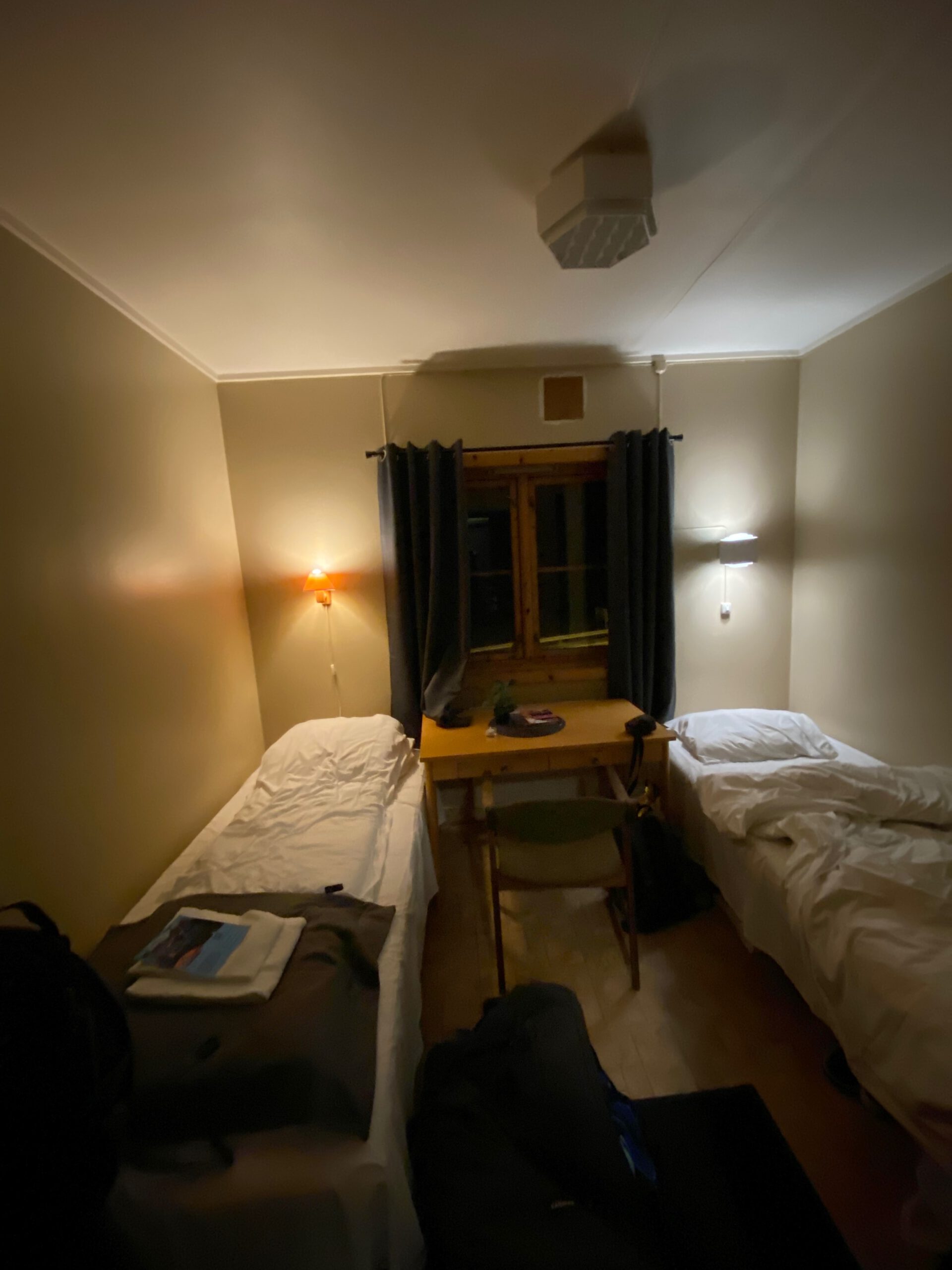 Gulbrakka Basecamp Glomfjord private bedroom, simple twin room with two single beds, wooden desk and soft lighting, providing a quiet and comfortable sleeping space in Northern Norway