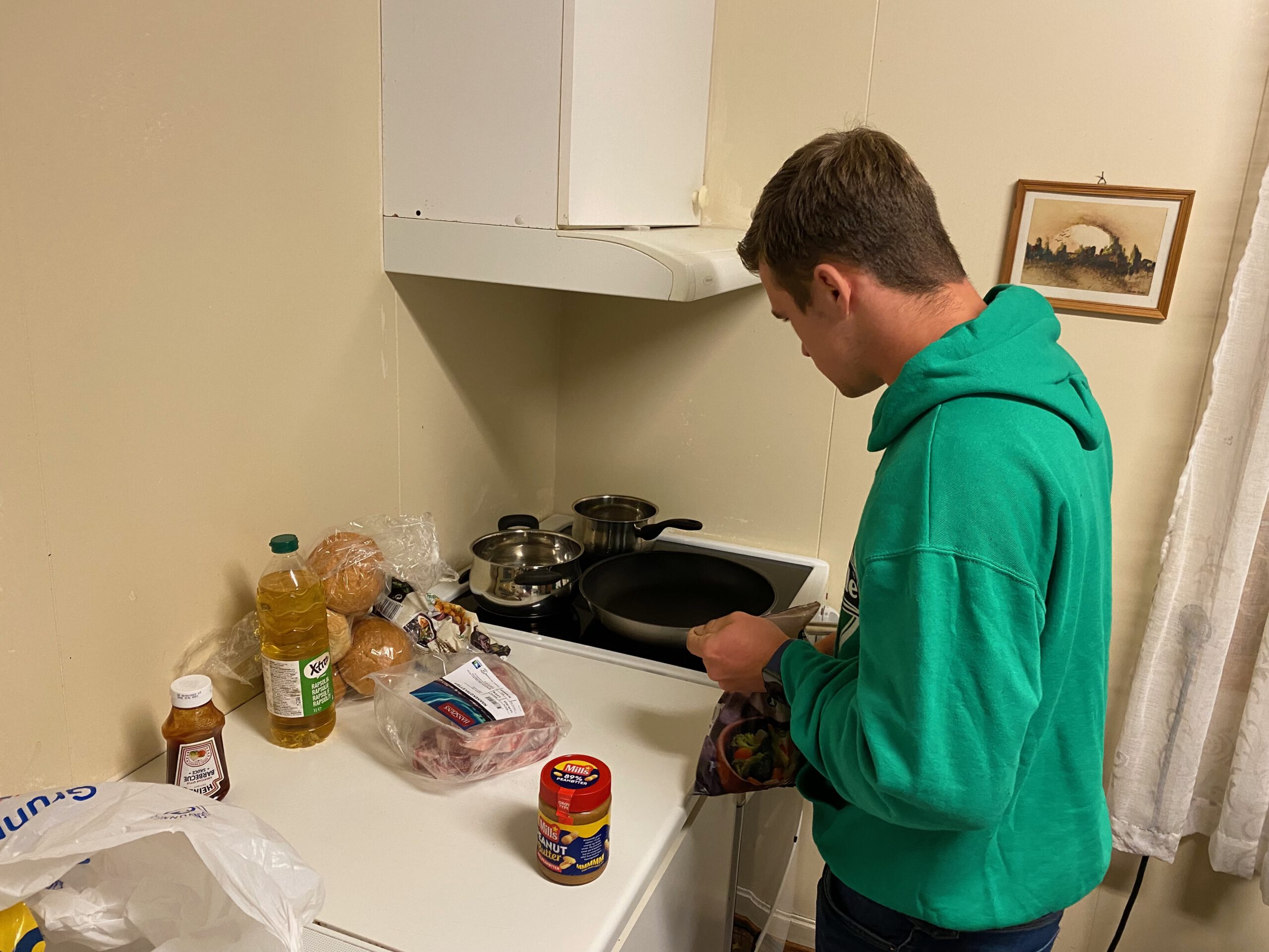 Gulbrakka Basecamp Glomfjord shared kitchen, traveler preparing dinner in the communal kitchen with basic cooking supplies during a stay in Northern Norway