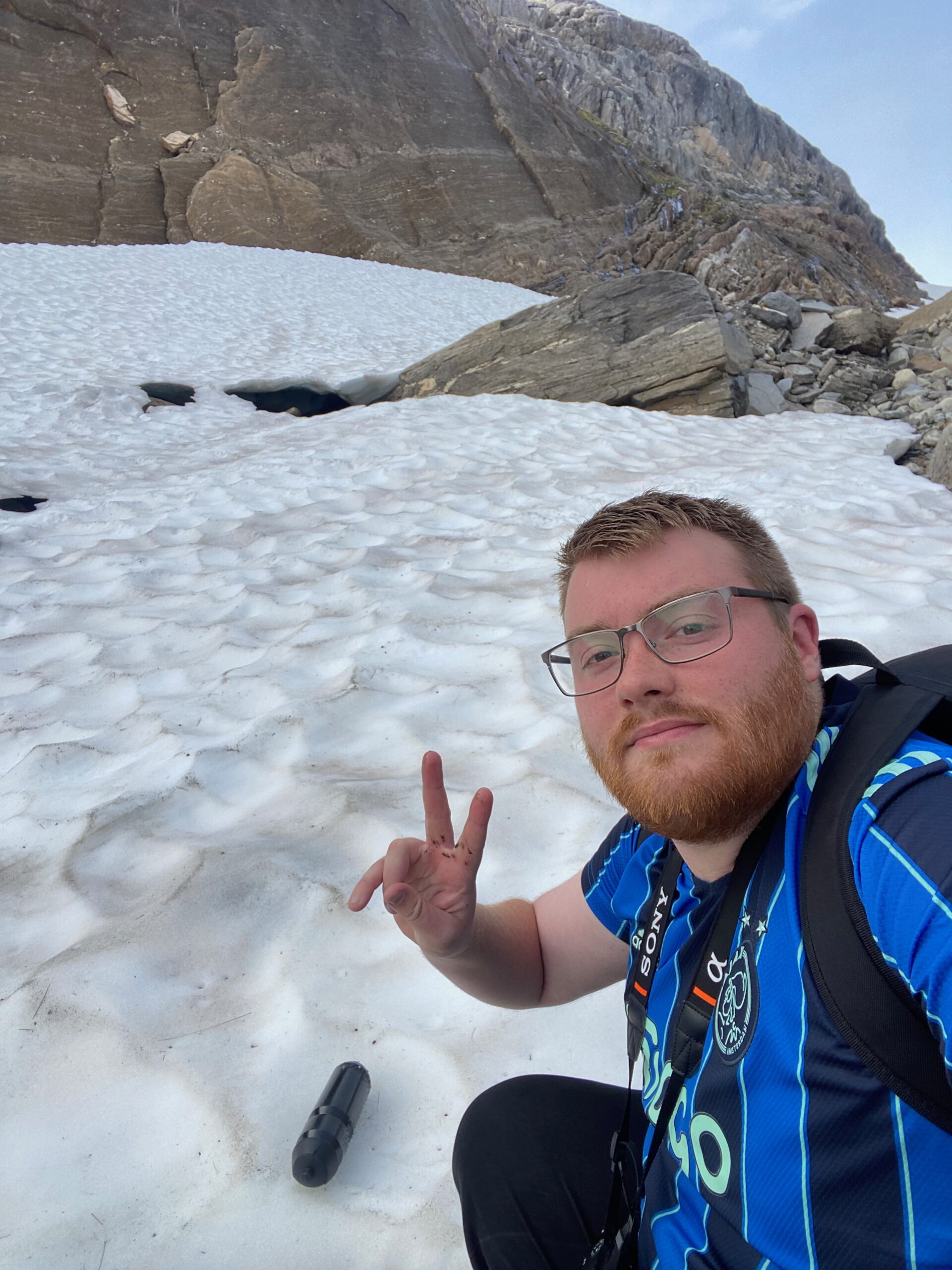 Gulbrakka Basecamp Glomfjord glacier hike moment, Timo van den Berg also known as Timeuw posing on a snowfield near rocky cliffs during a mountain hike in Northern Norway