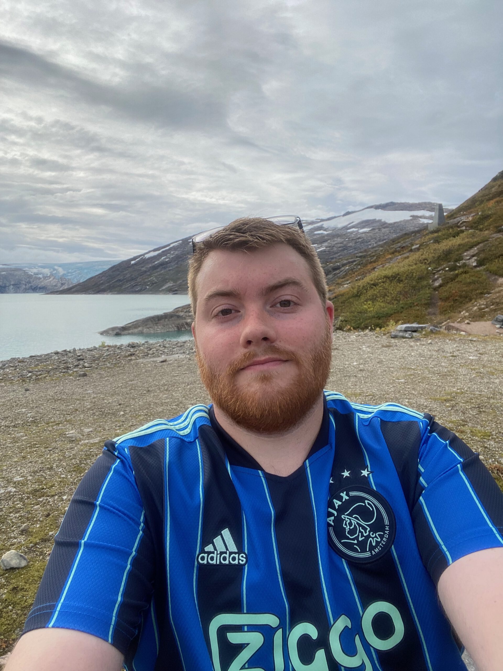 Gulbrakka Basecamp Glomfjord travel selfie, Timo van den Berg also known as Timeuw standing by a mountain lake surrounded by rocky hills and Arctic landscape