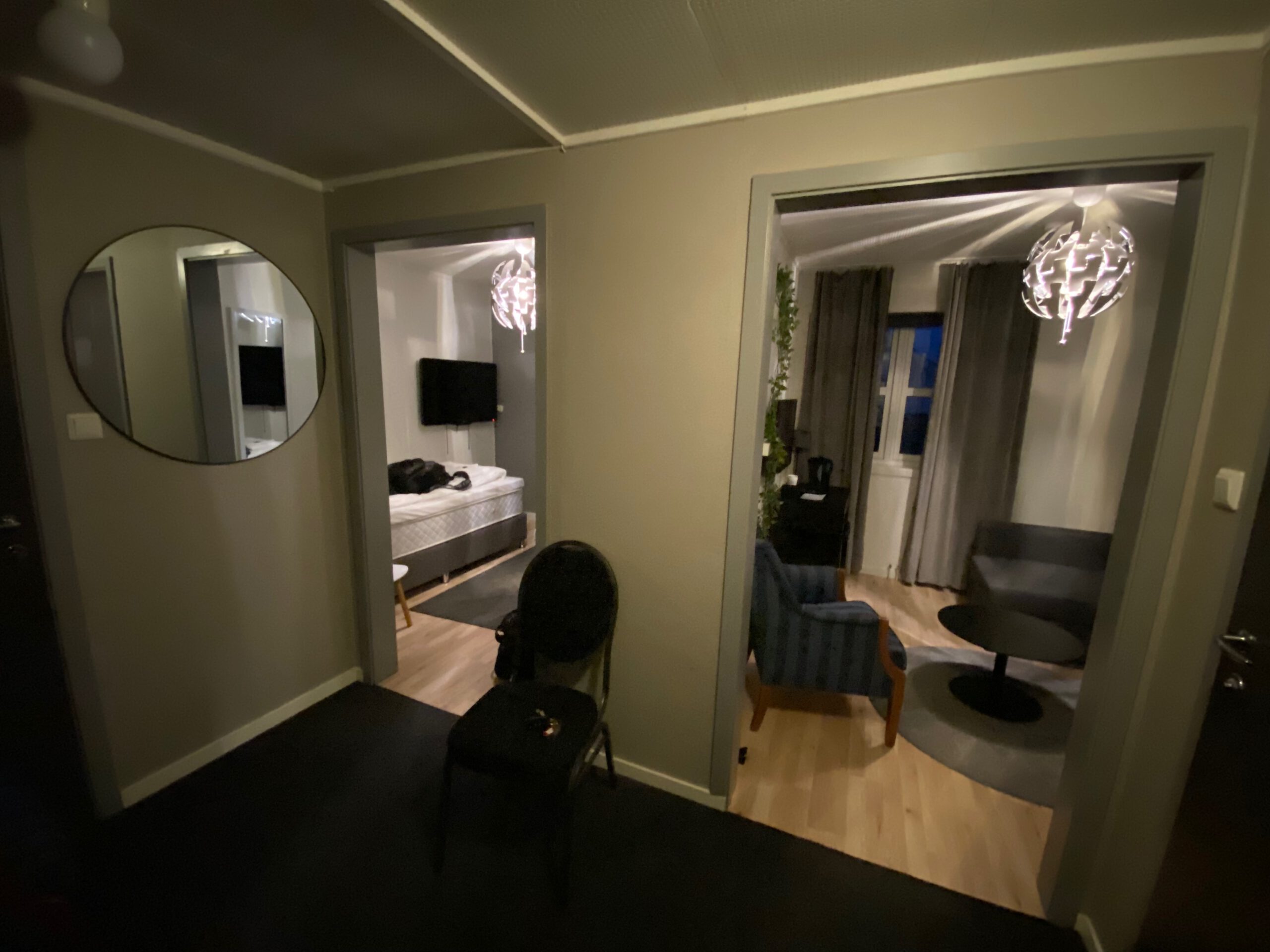 Hallway view inside Mosjøen Romutleie Sentrum 3 showing the entrance area with mirror, chair, and access to both the bedroom and living room, a compact apartment style room layout in Mosjøen, Norway