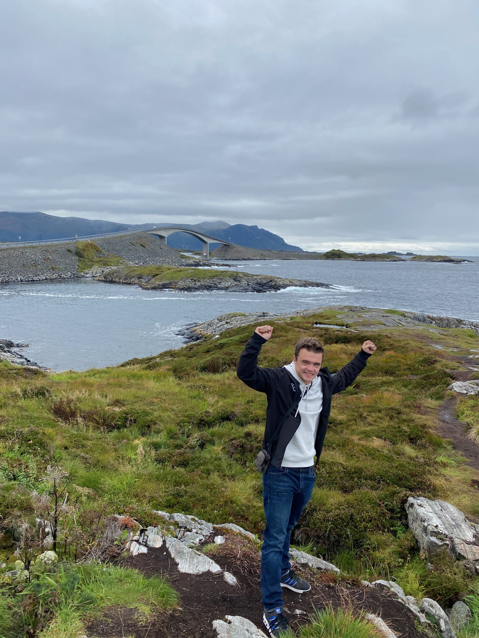 Peter Smit posing with raised arms at Atlantic Ocean Road Norway near Storseisundet Bridge in Møre og Romsdal