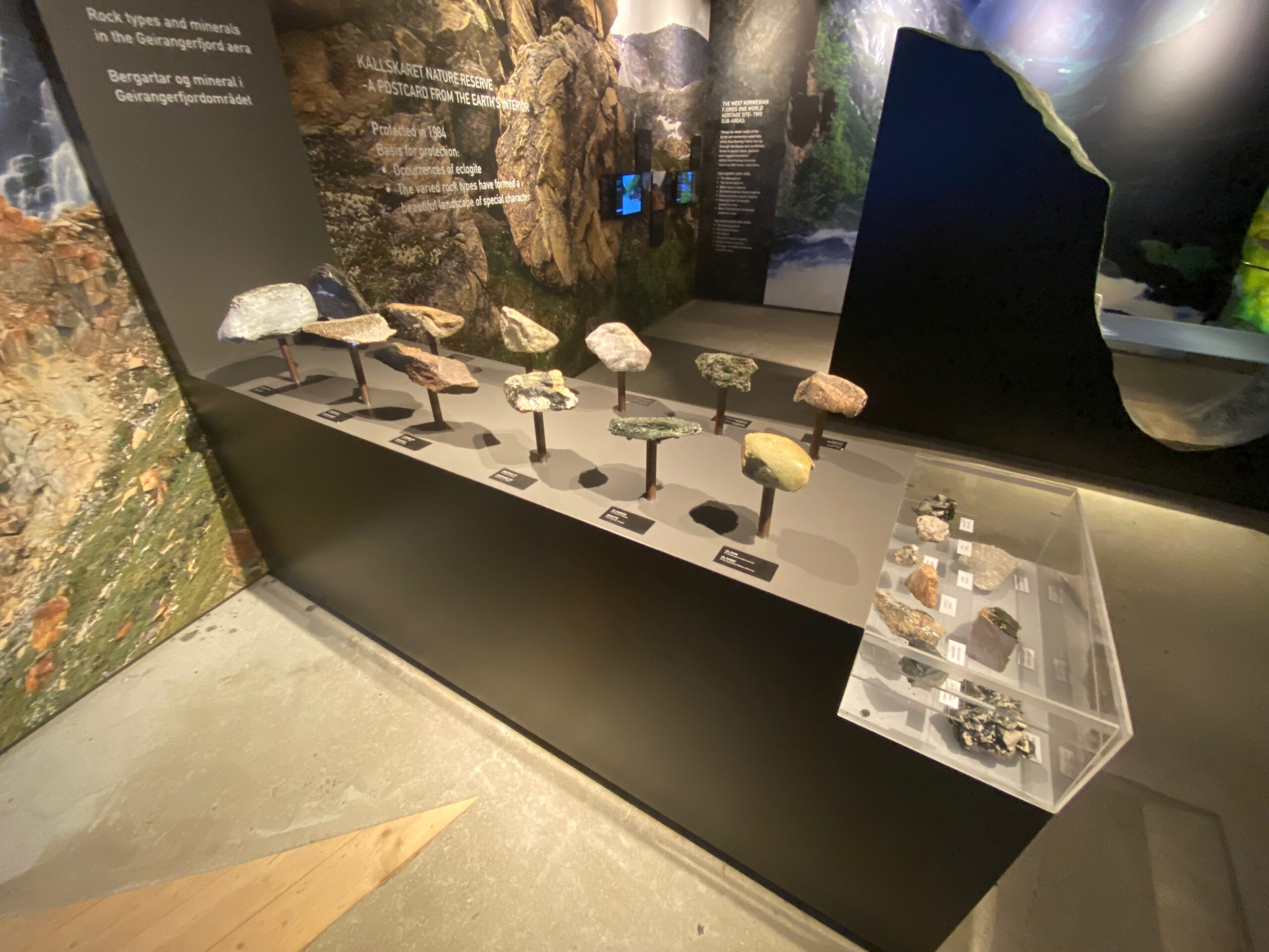 Rock and mineral exhibition at Norsk Fjordsenter Geiranger displaying geological samples from the UNESCO World Heritage Geirangerfjord area with educational panels about rock types and natural history