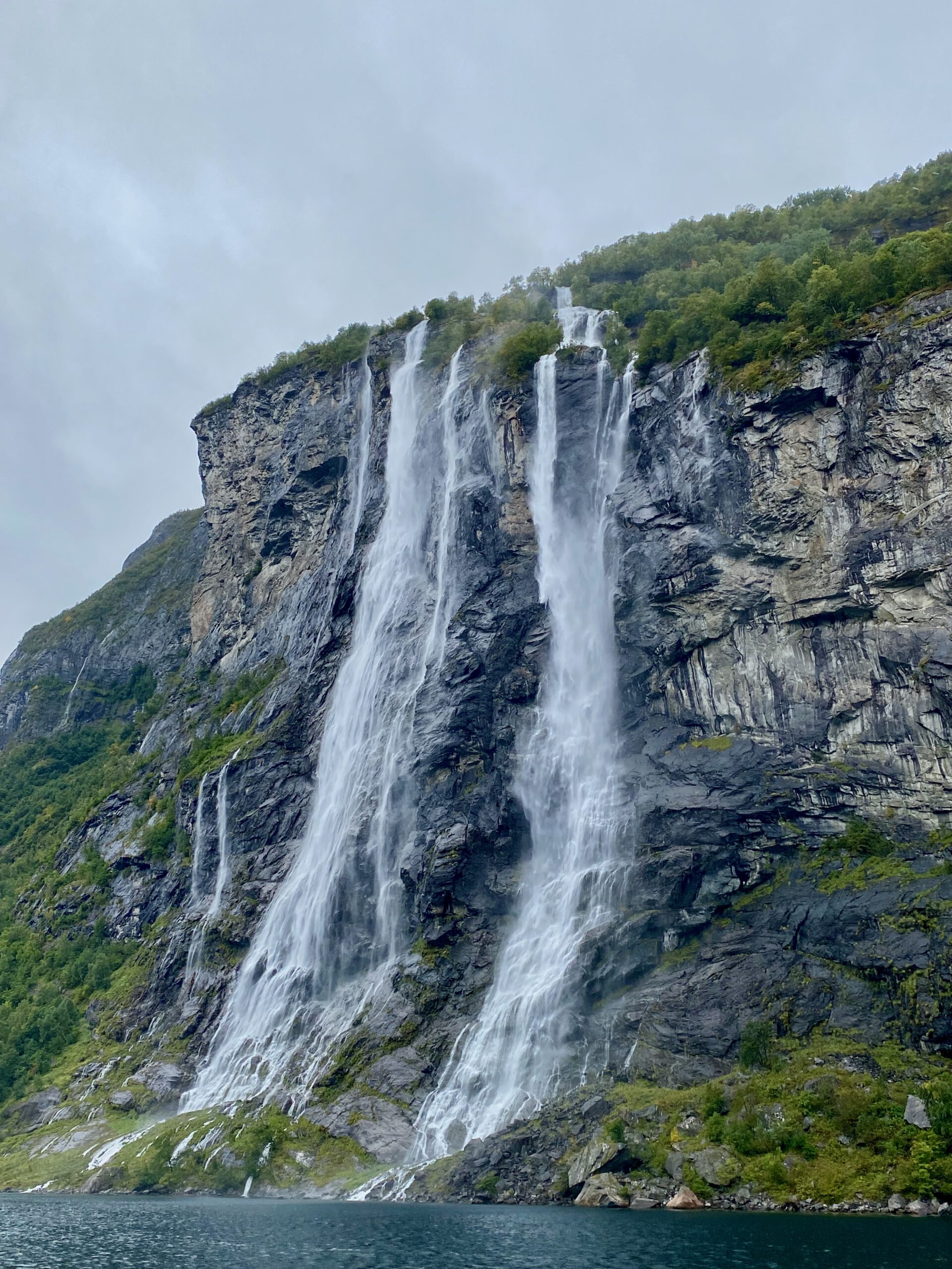 Wide angle view of the Seven Sisters waterfall in Geirangerfjord during the Geiranger Fjord and Waterfalls Sightseeing Boat Trip cascading down steep granite cliffs