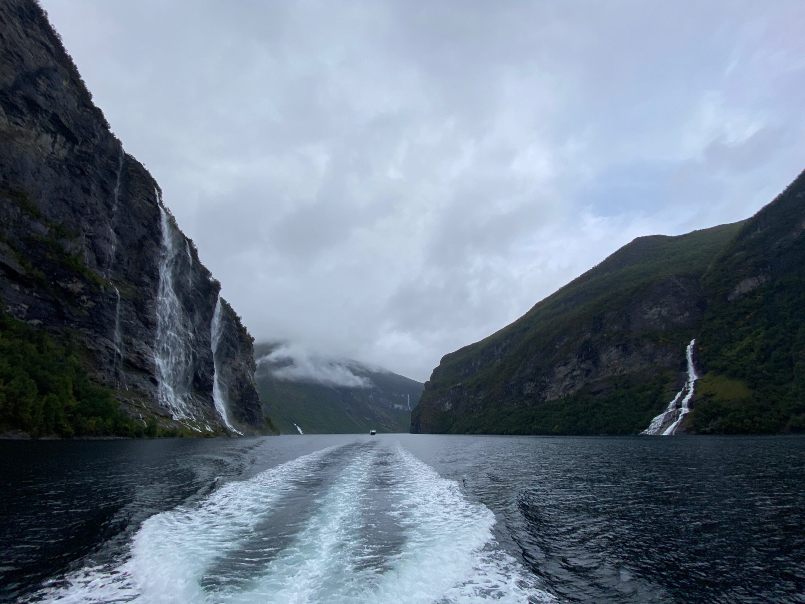 Wake behind the boat during the Geiranger Fjord and Waterfalls Sightseeing Boat Trip passing the Seven Sisters Waterfall and steep cliffs in UNESCO Geirangerfjord